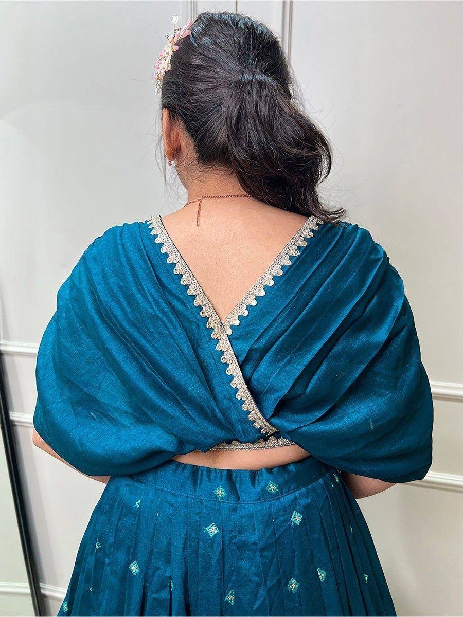 Teal velvet lehenga choli with embroidered back neckline and floral hair accessory
