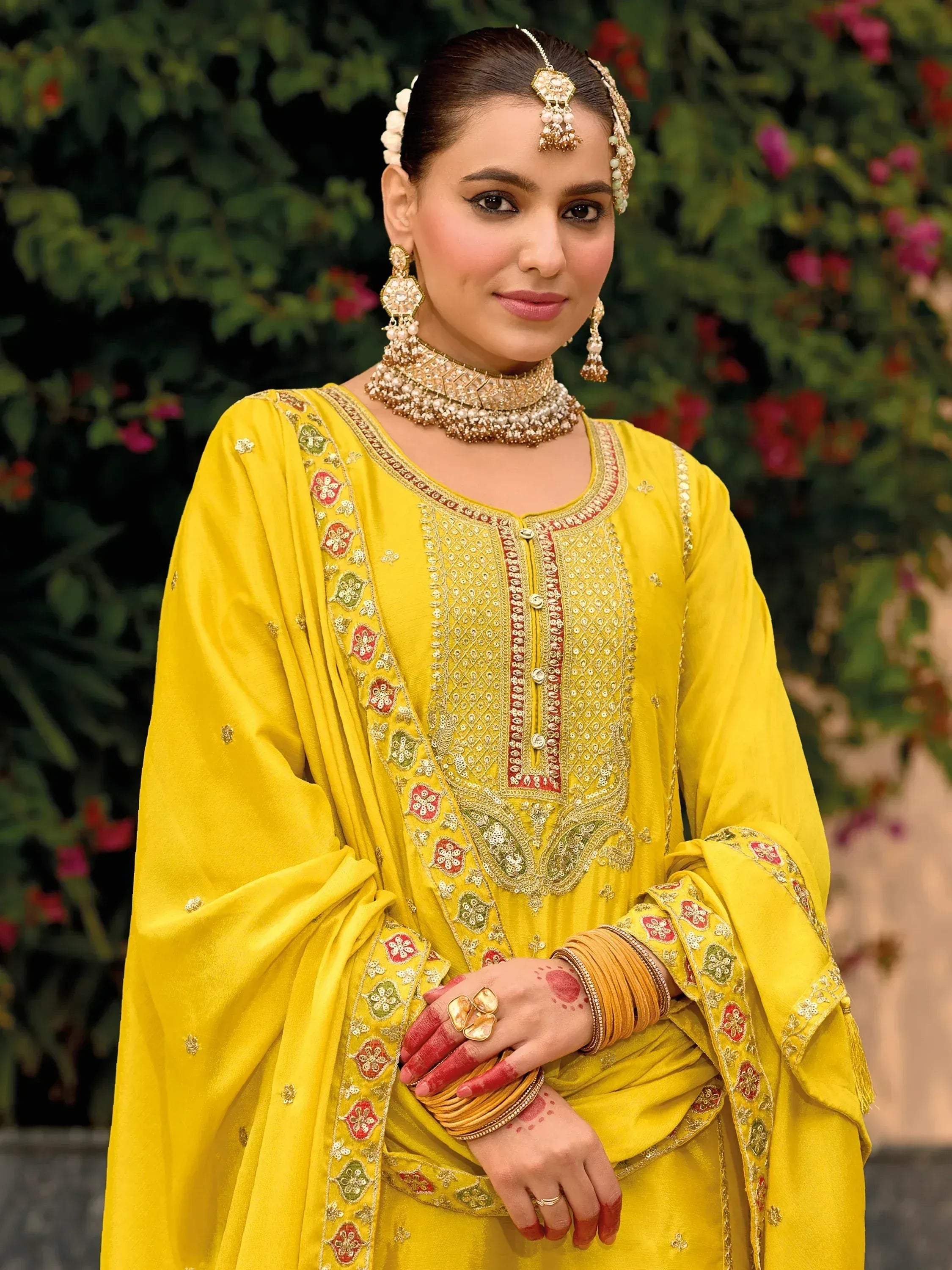 Yellow embroidered salwar kameez with traditional jewelry and henna, perfect for ethnic occasions