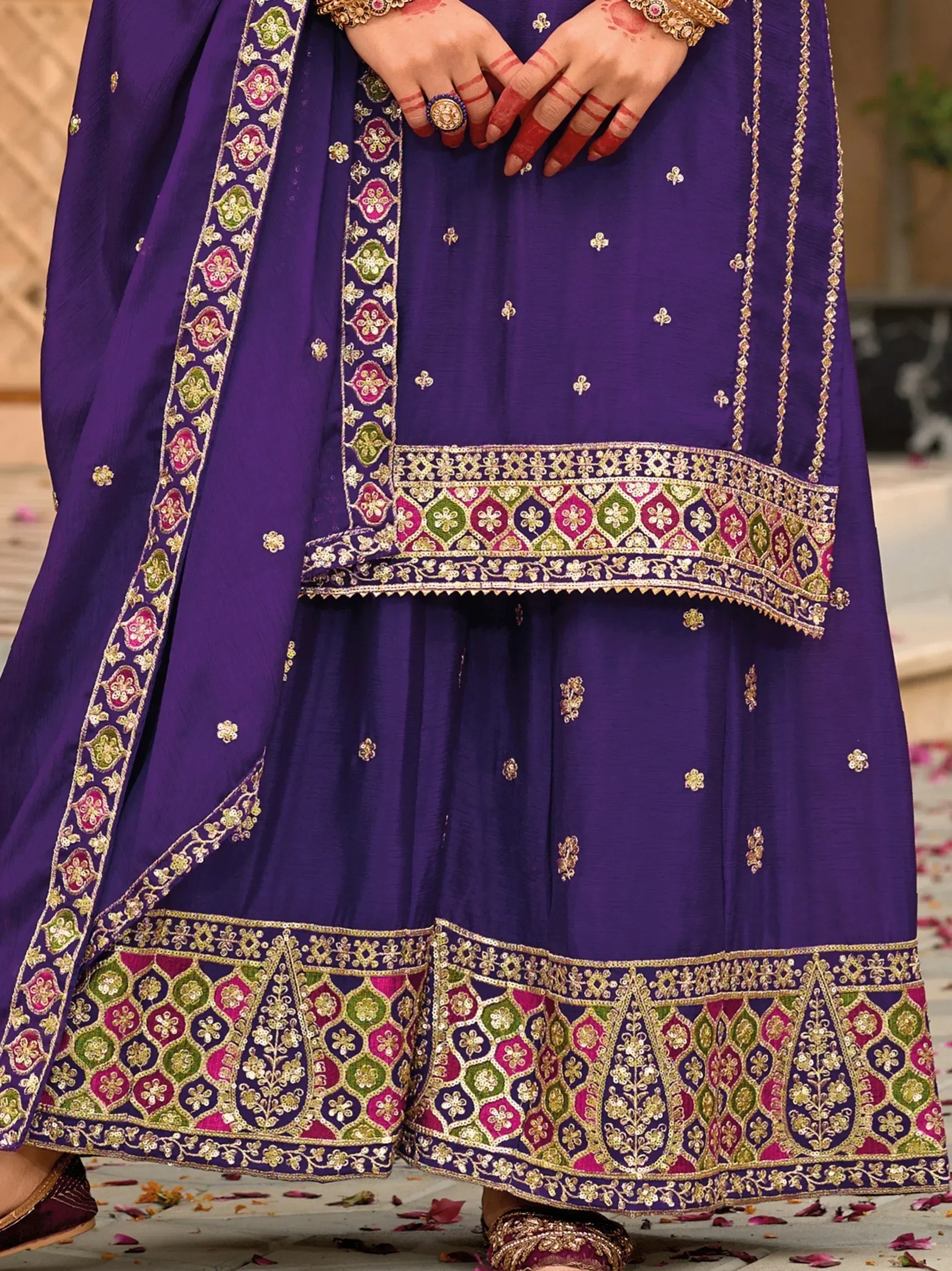 Purple embroidered Indian ethnic gown with floral border, henna hands, and gold jewelry