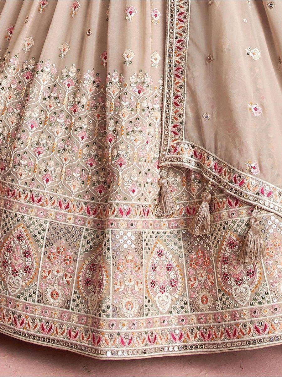 Beige designer lehenga with intricate floral embroidery, mirror work, and tassels for Indian ethnic wear
