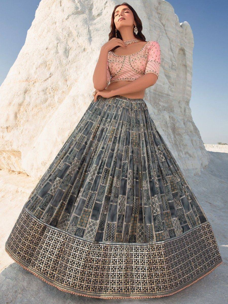 Woman in elegant Indian lehenga choli with embroidered grey skirt and pink blouse, styled for festive occasions