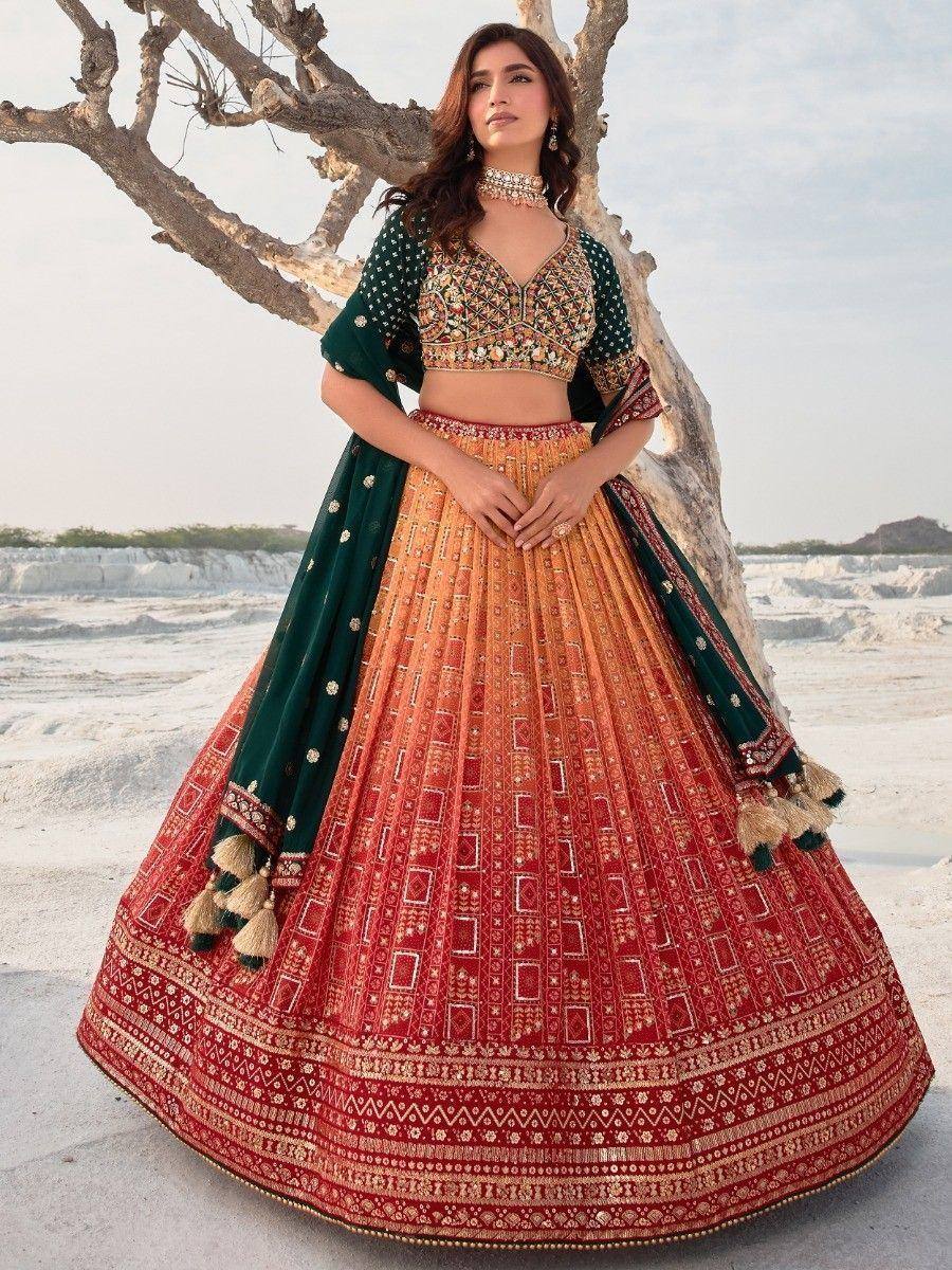 Designer lehenga choli with embroidered blouse, red-orange skirt, and green dupatta, perfect for Indian weddings.