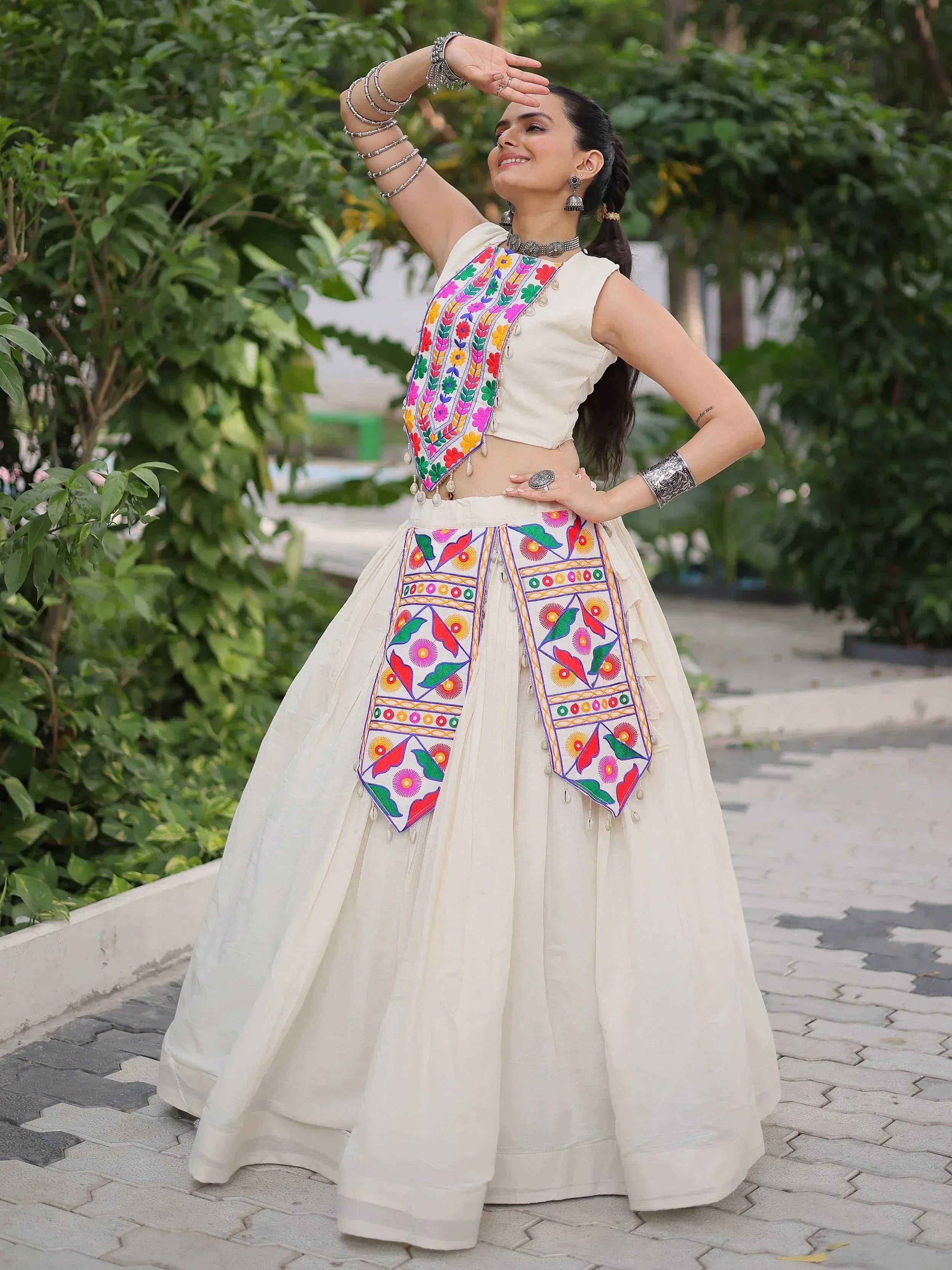 Woman in white ethnic lehenga choli with colorful floral embroidery, perfect for Indian festivals and weddings.