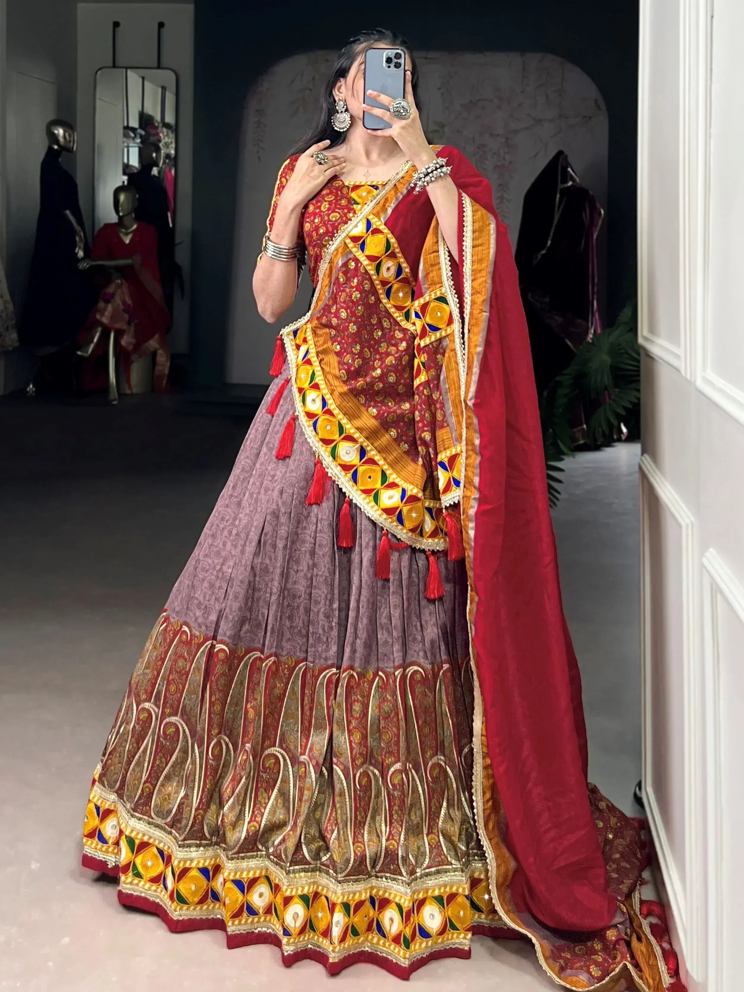 Woman in vibrant red and gold embroidered lehenga choli with mirror work, perfect for Indian ethnic occasions.
