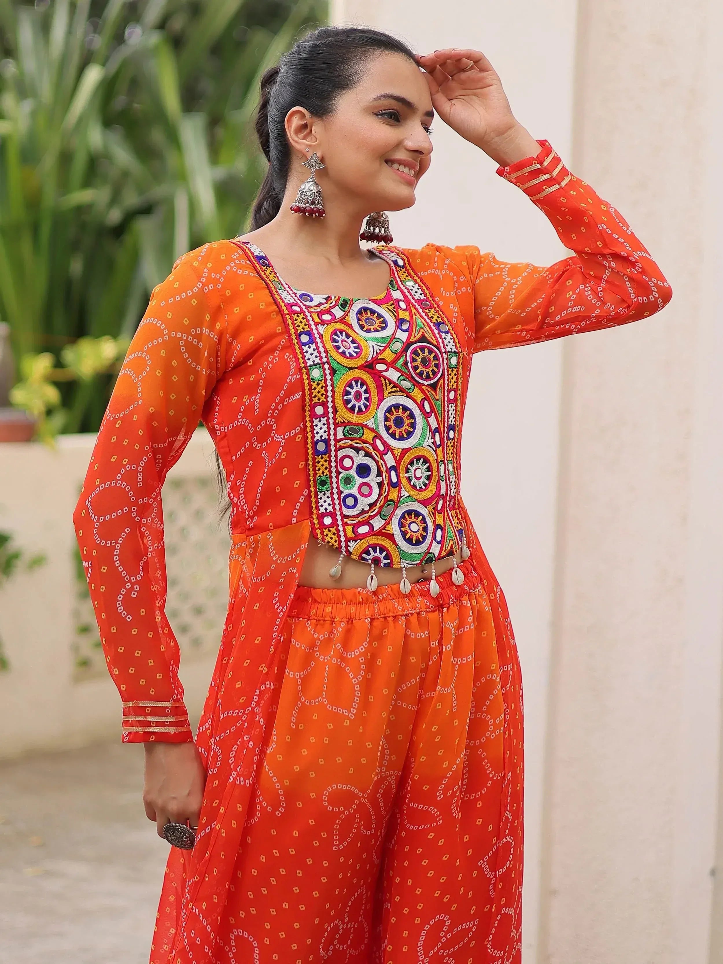Vibrant orange ethnic wear with colorful mirror embroidery, perfect for Indian festivals and celebrations.