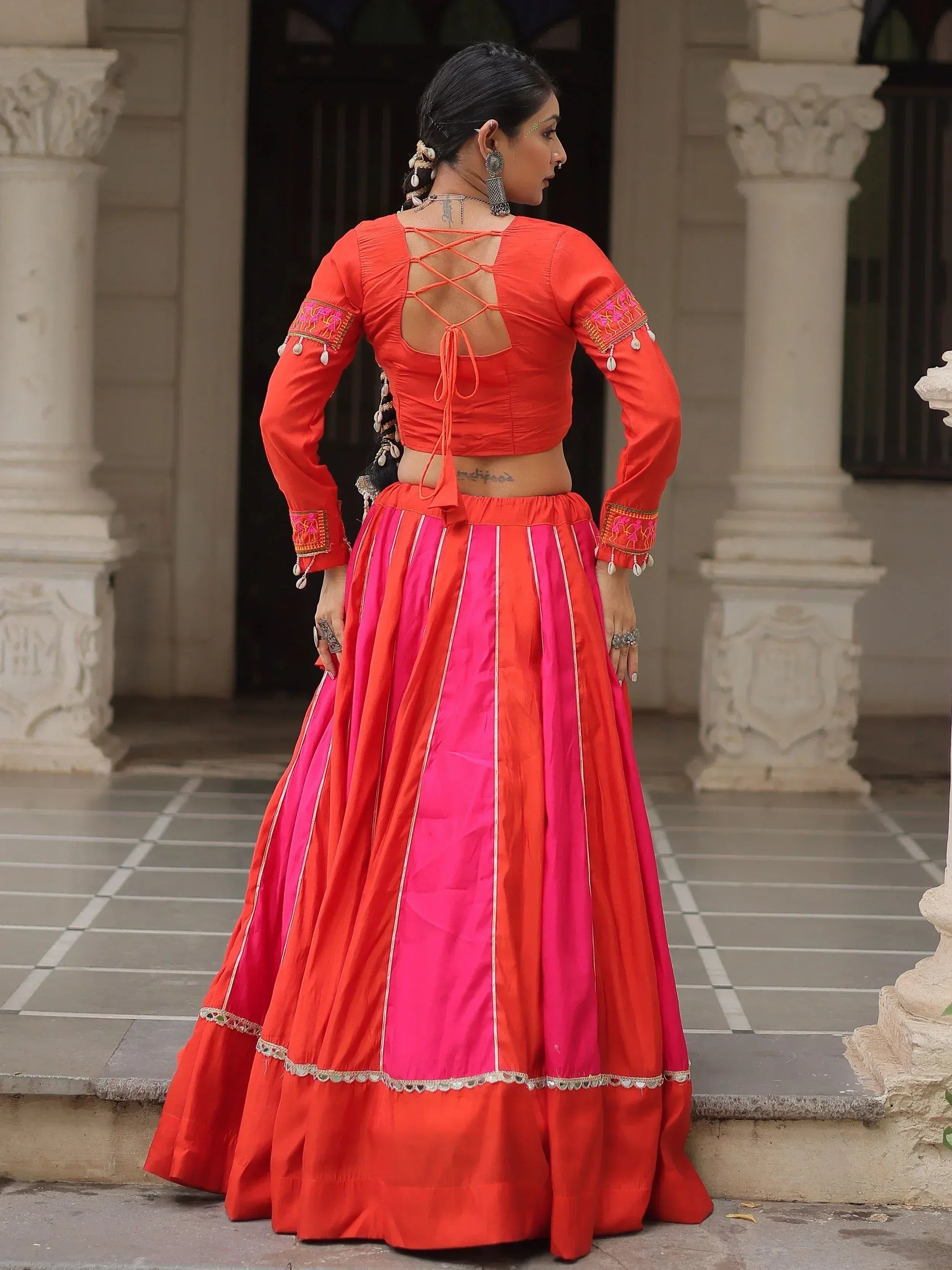 Vibrant orange and pink lehenga choli with crisscross back blouse, perfect for Indian ethnic wear occasions.