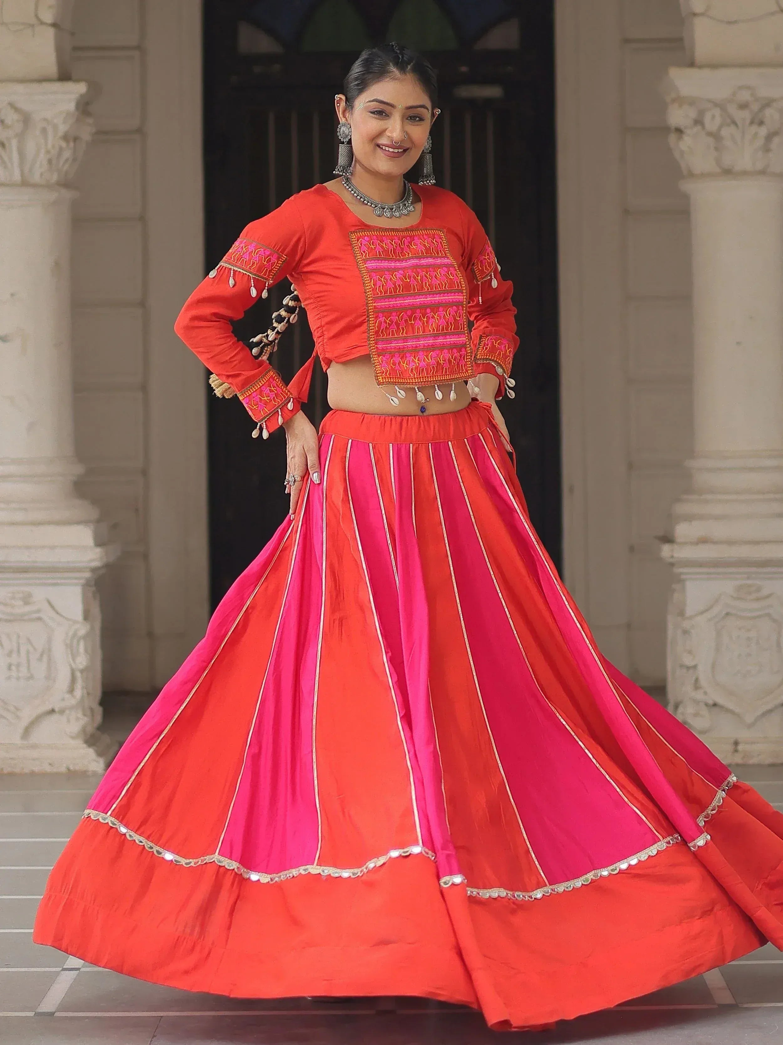 Vibrant red and pink ethnic lehenga choli with intricate embroidery and mirror work, perfect for festive occasions.