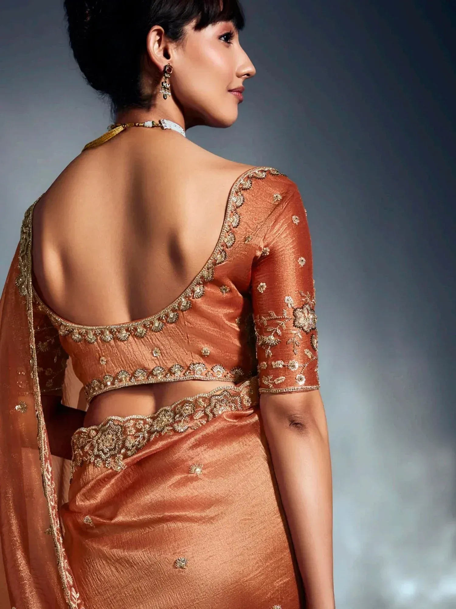 Elegant peach saree with gold embroidery and backless blouse, perfect for Indian ethnic occasions.