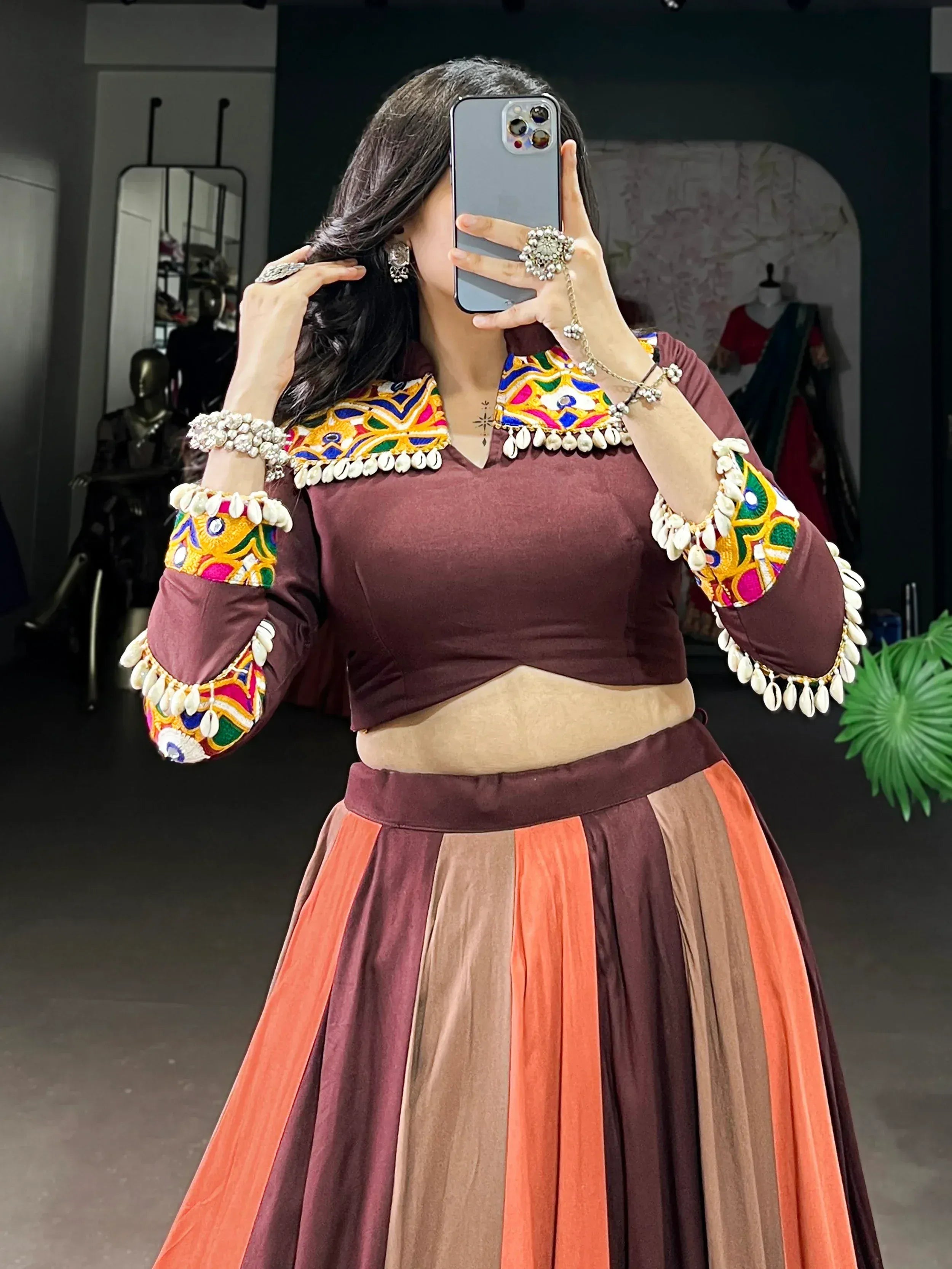 Woman in maroon ethnic lehenga choli with colorful mirror work and shell embroidery, perfect for festive occasions.