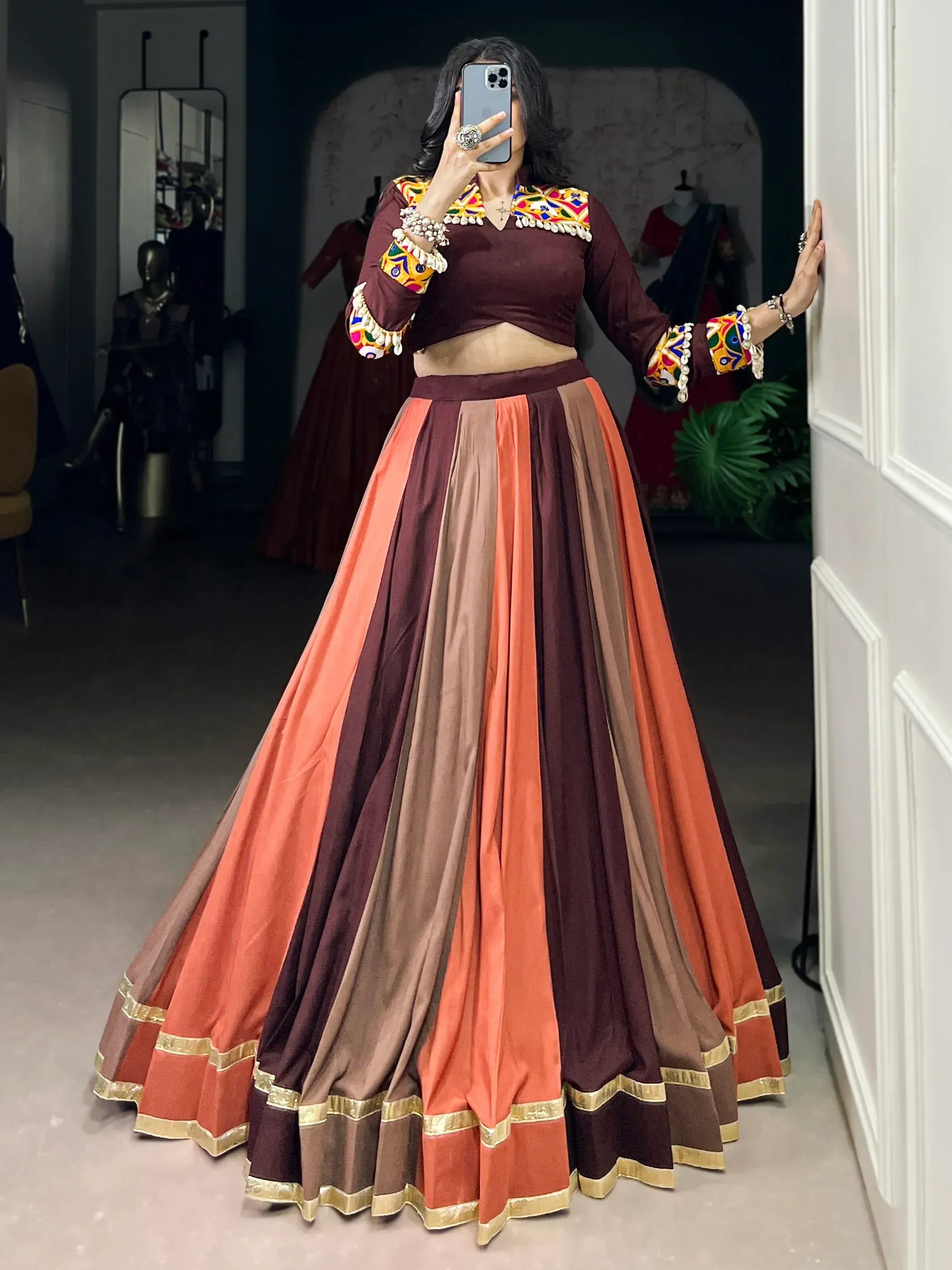 Maroon and orange ethnic lehenga choli with colorful mirror work and gold trim, perfect for Indian celebrations