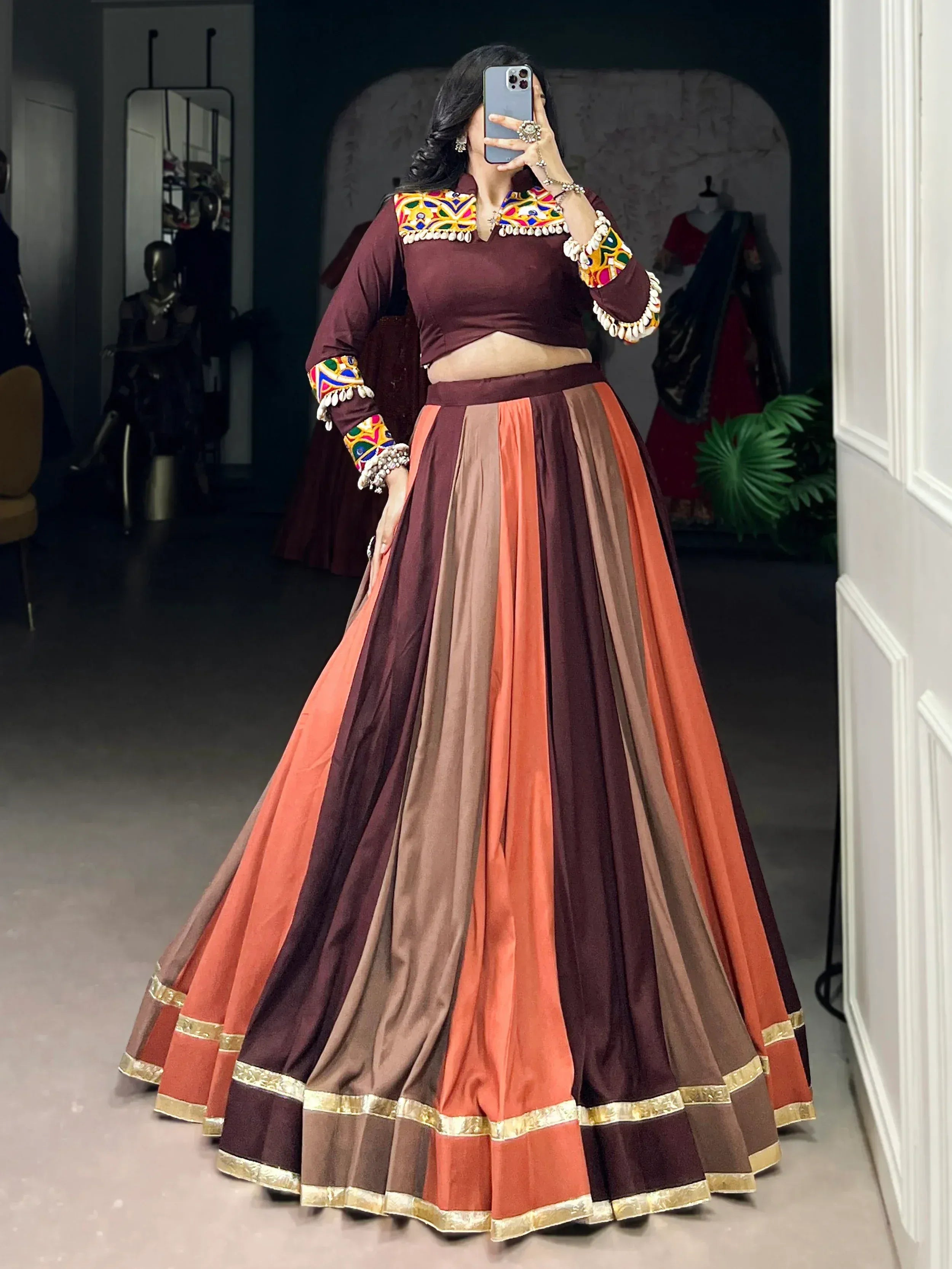 Maroon and orange ethnic lehenga choli with colorful mirror work and gold trim, perfect for Indian weddings or festivals.