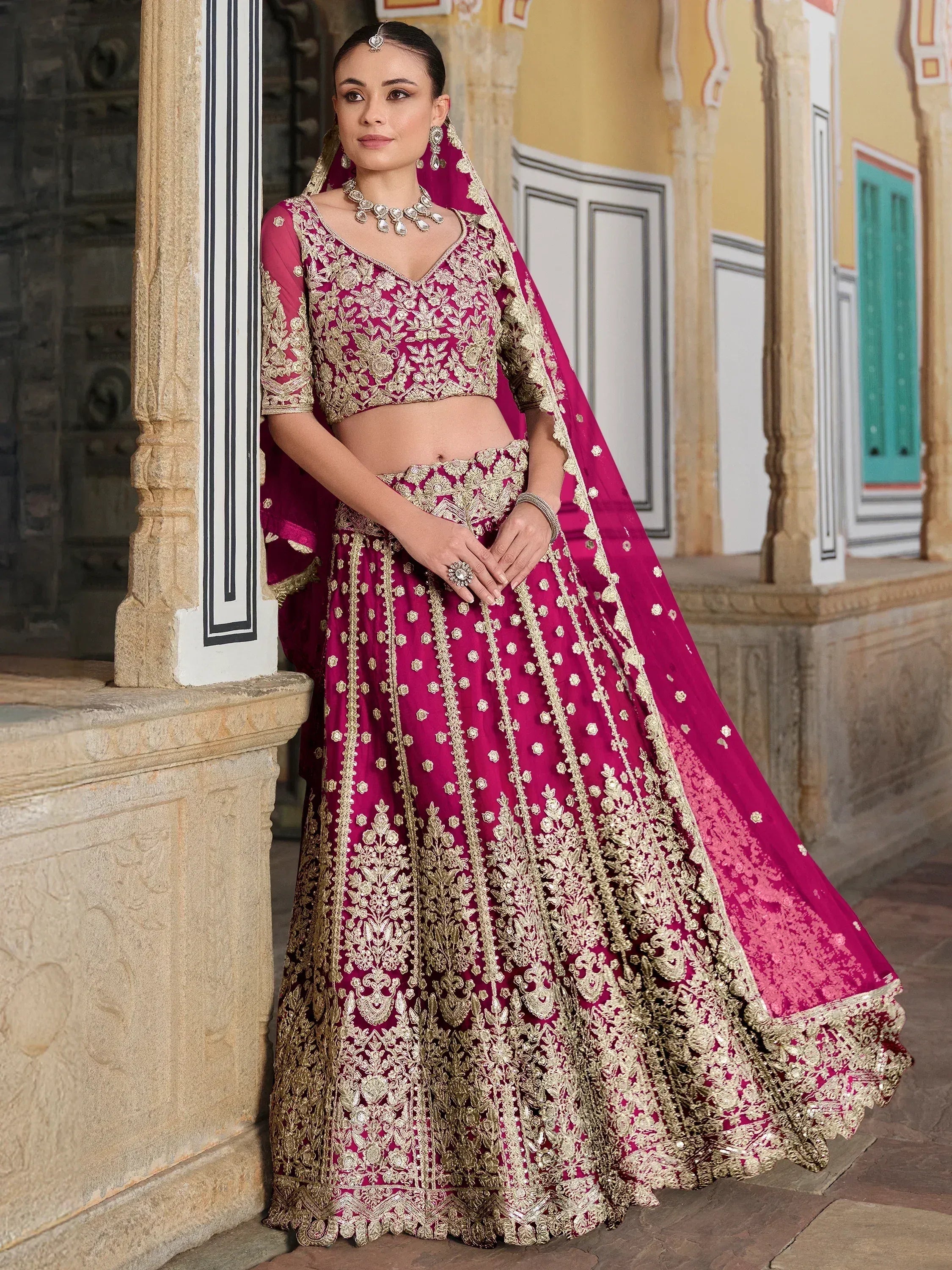 Elegant magenta lehenga choli with gold embroidery, perfect for Indian weddings and festive occasions.