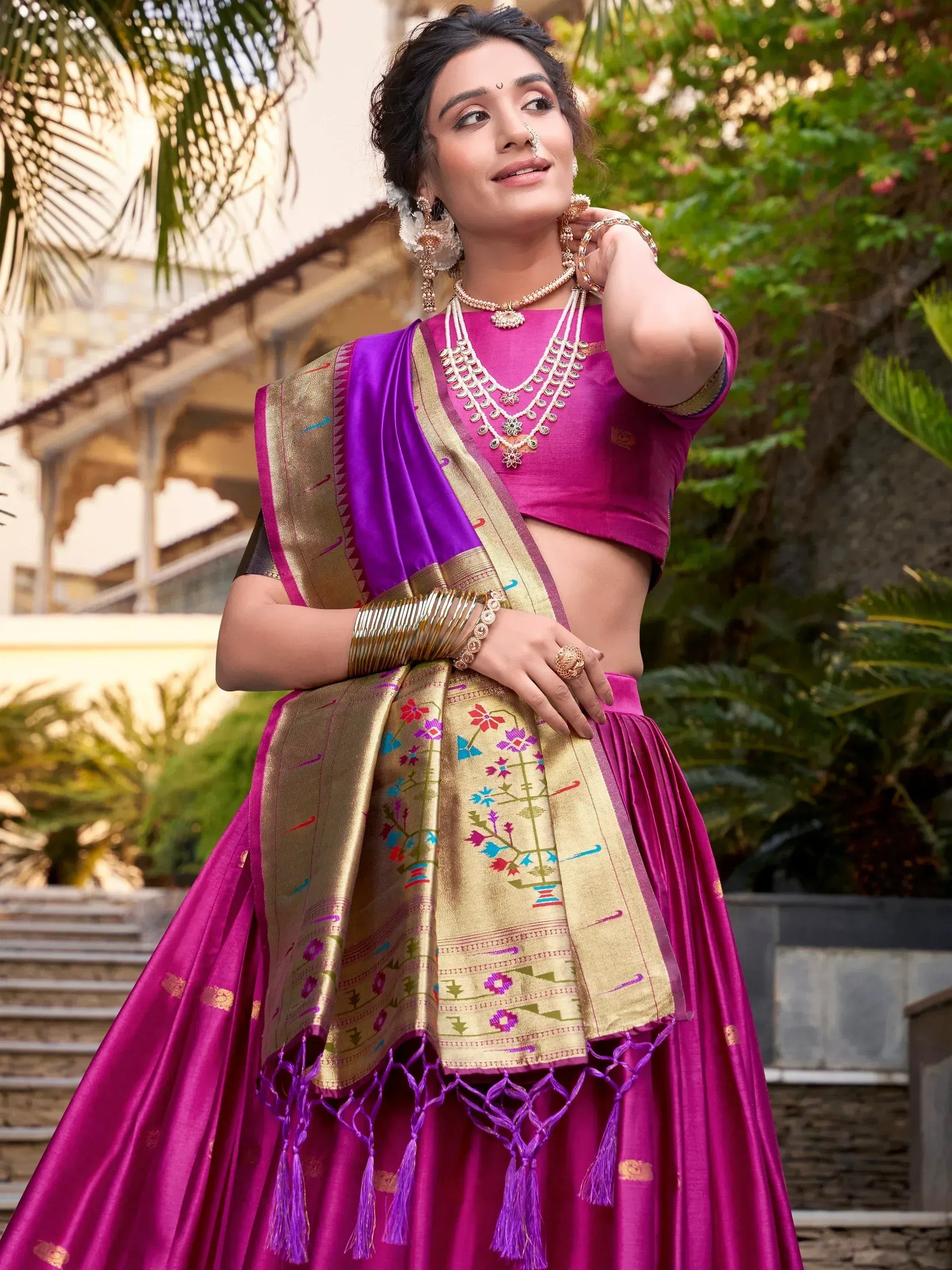 Woman in vibrant pink and gold designer lehenga choli with purple dupatta, perfect for Indian ethnic occasions