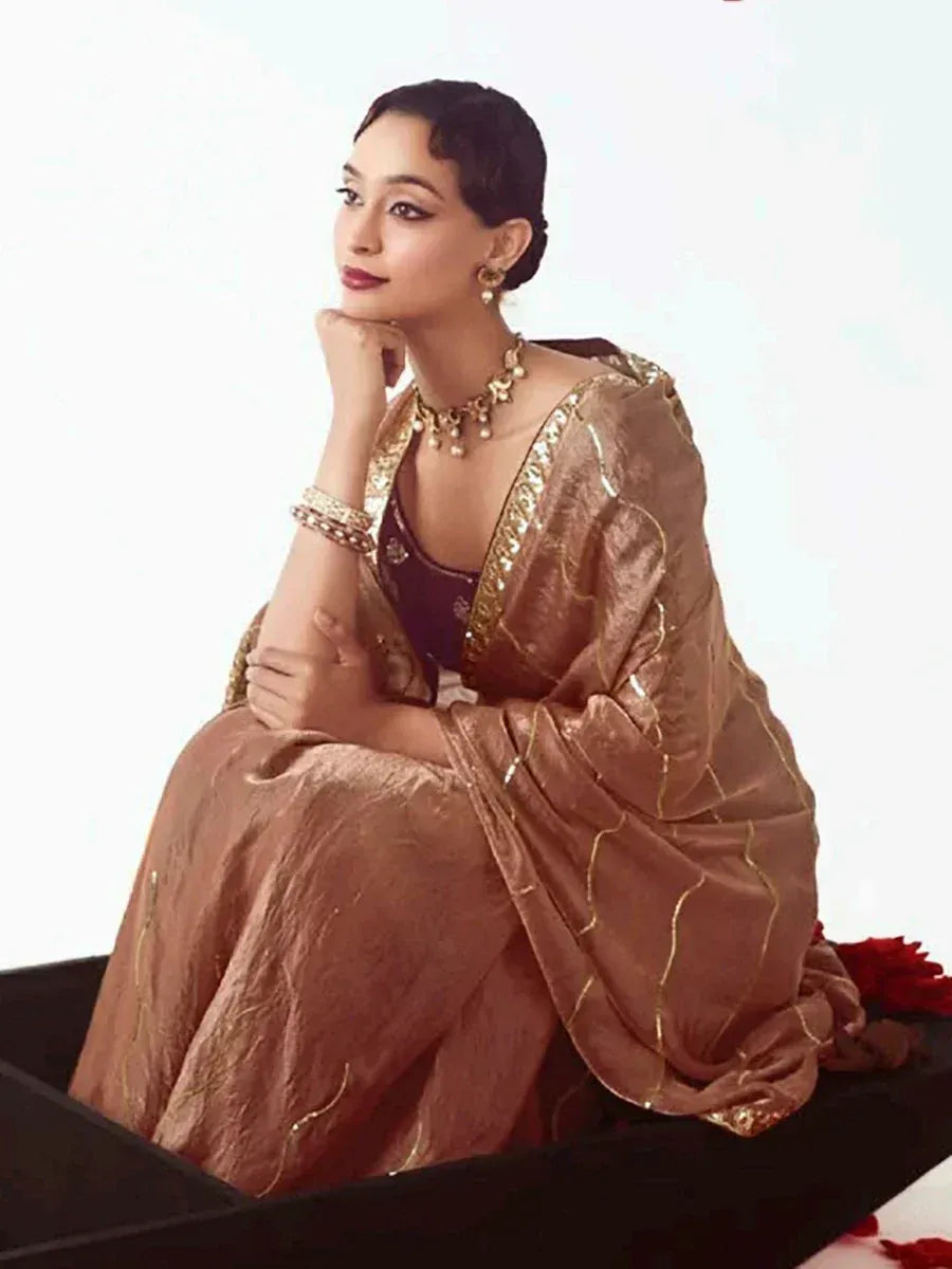 Elegant woman in golden brown designer lehenga choli with intricate embroidery and traditional jewelry