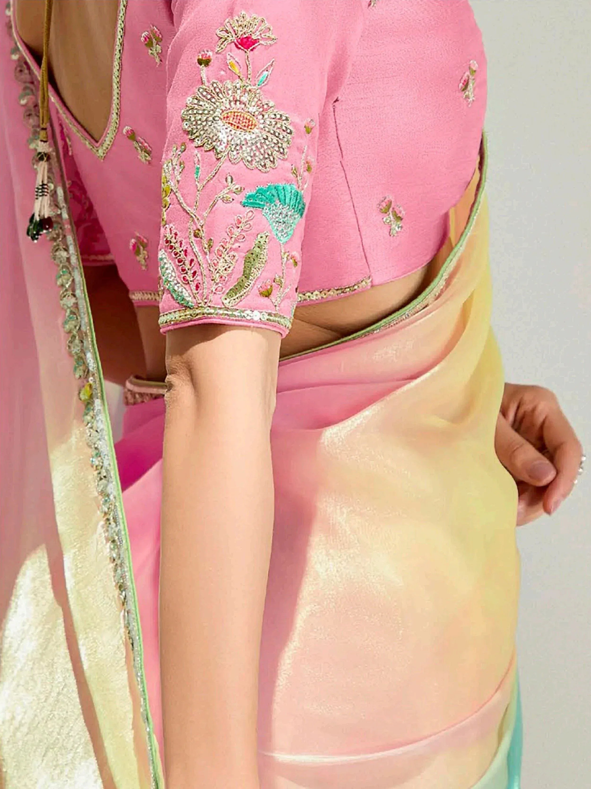 Pink embroidered blouse with floral zari work, paired with pastel saree for Indian ethnic wear
