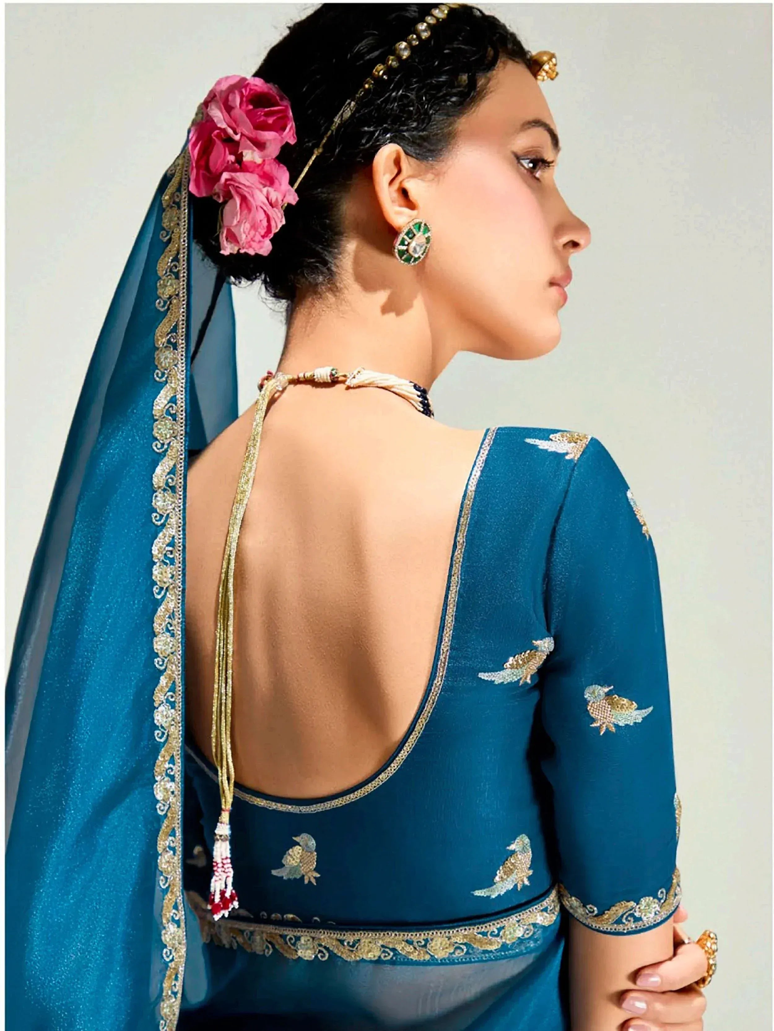 Teal blue designer lehenga choli with bird embroidery, open back, and floral hair accessory