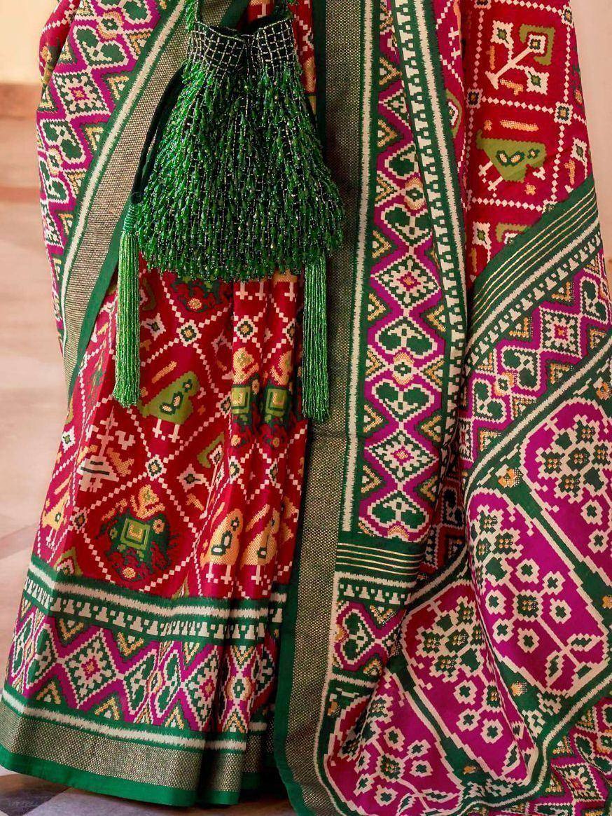 Vibrant red and green ethnic lehenga with intricate geometric patterns and beaded tassels