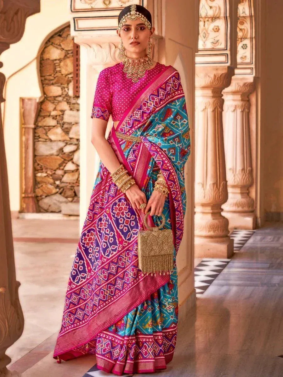 Vibrant pink and blue printed saree with ethnic jewelry, perfect for Indian weddings or festive occasions