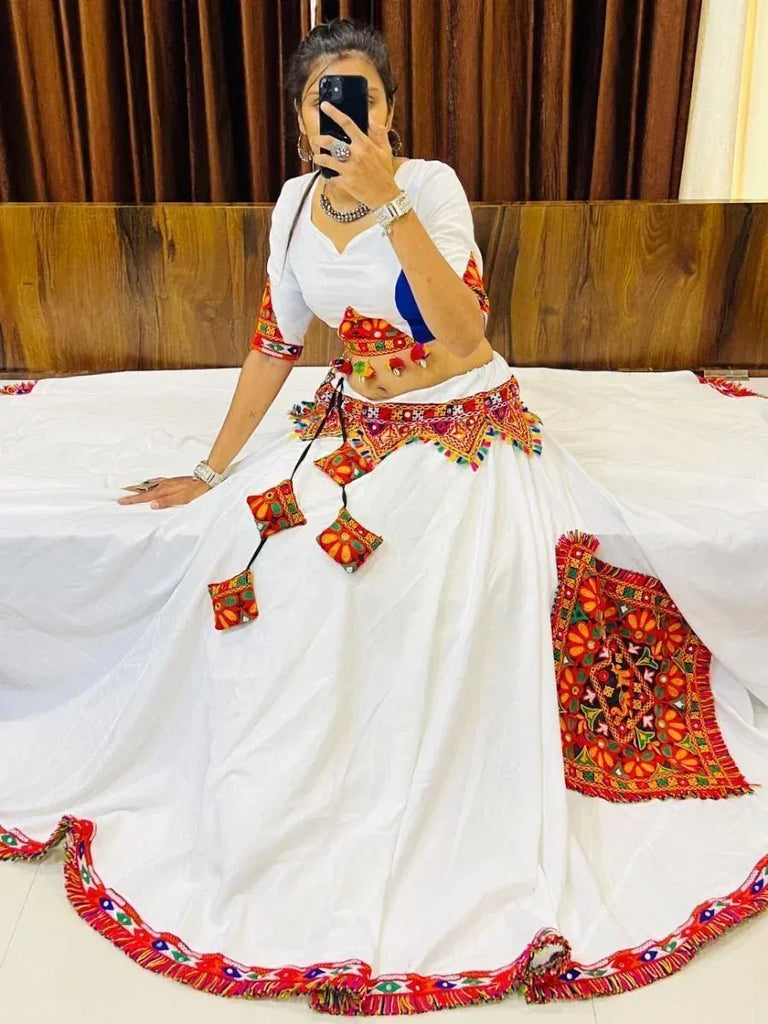White embroidered lehenga choli with colorful mirror work and tassels, perfect for ethnic occasions