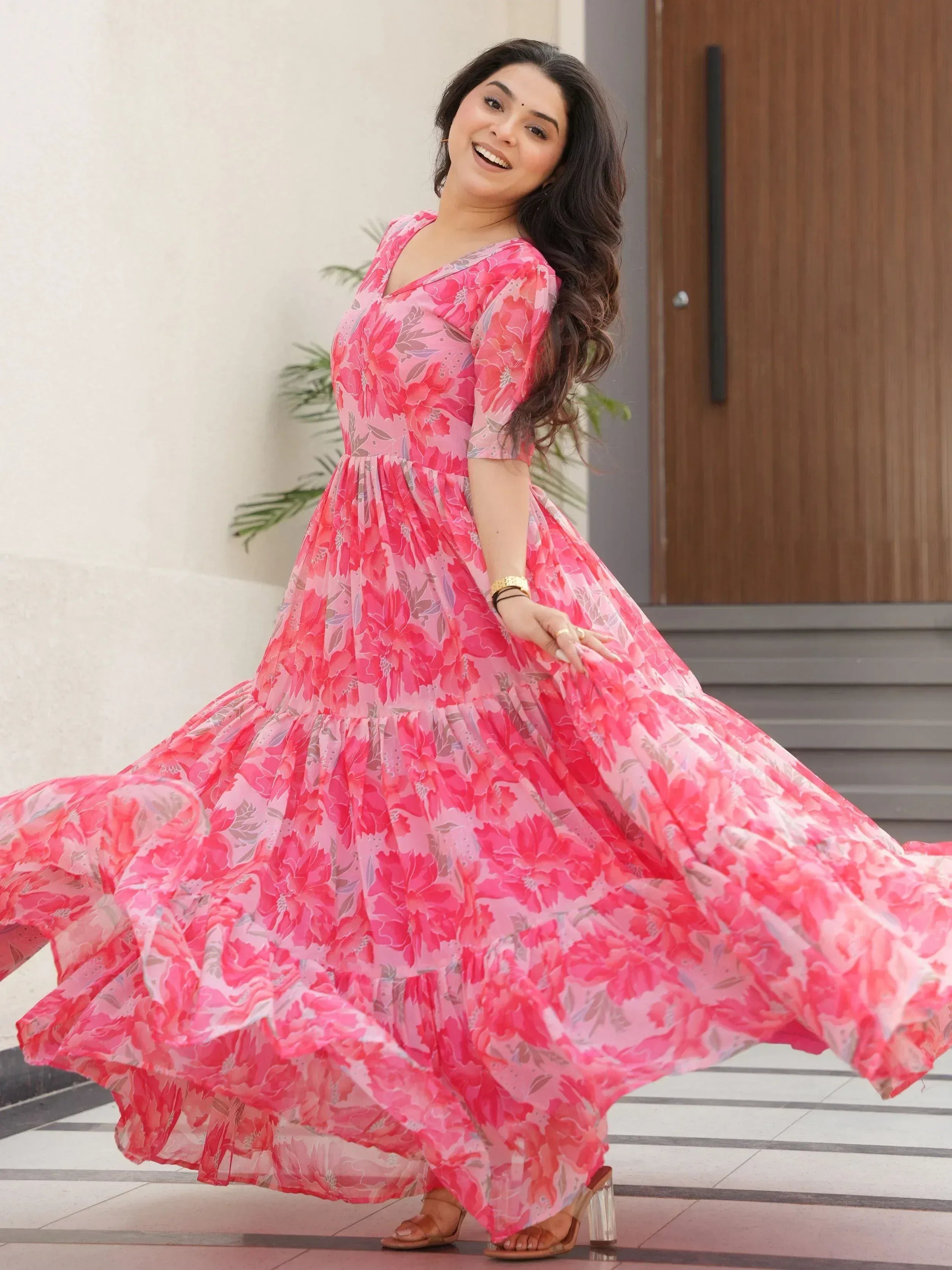 Woman twirling in pink floral ethnic gown, perfect for festive occasions and parties.