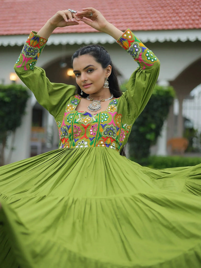Woman in green embroidered ethnic gown with mirror work, twirling outdoors