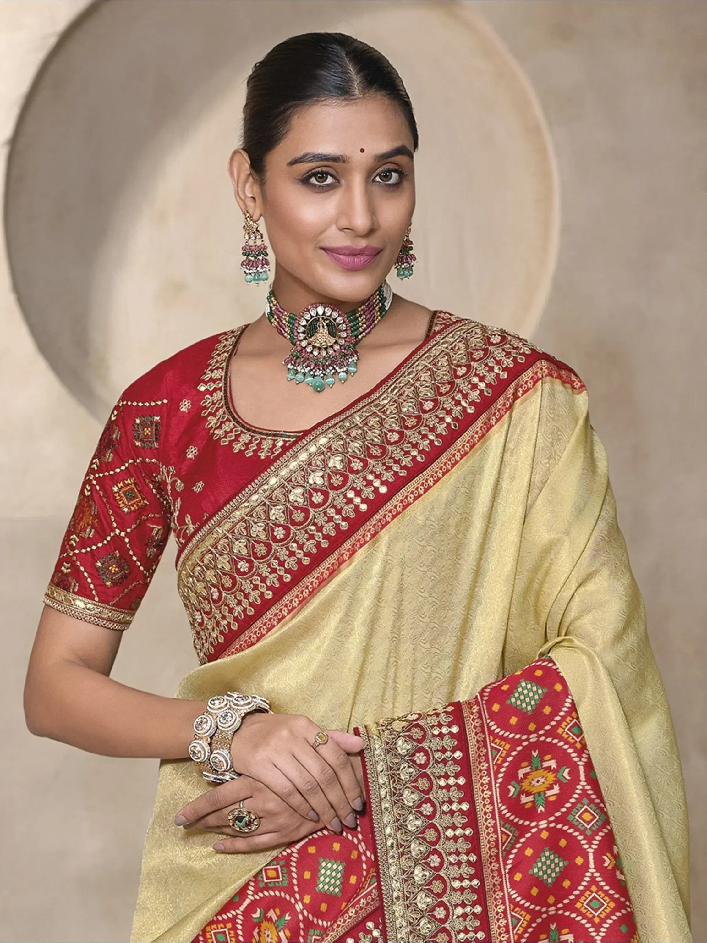 Elegant Indian saree with red and gold embroidery, paired with traditional jewelry for festive occasions.