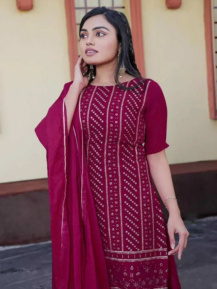 Woman wearing maroon printed salwar kameez with dupatta, standing outdoors