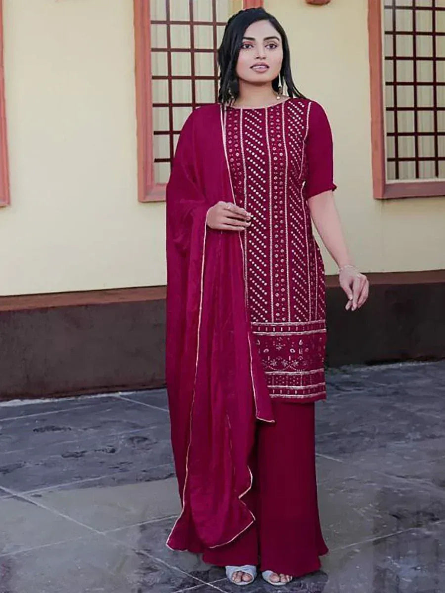 Woman in maroon embroidered salwar kameez with dupatta, standing outdoors