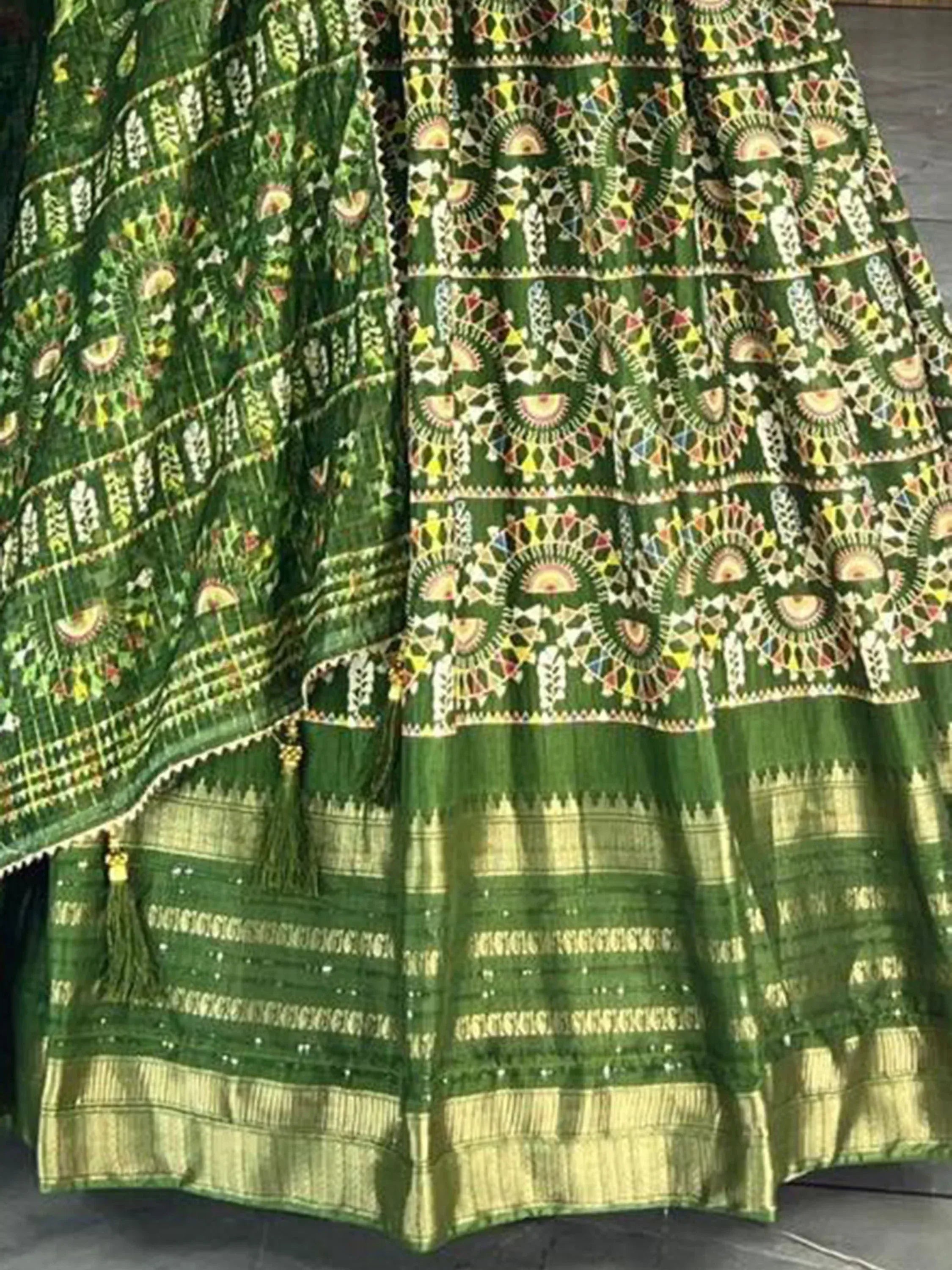 Green ethnic lehenga choli with intricate embroidery and gold border, perfect for Indian weddings and festivals.