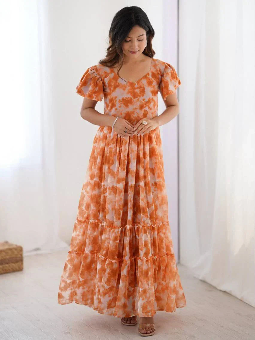 Woman wearing an orange tie-dye ethnic gown with flutter sleeves in a bright room