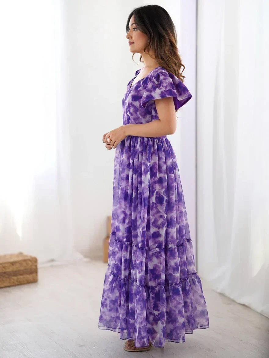 Woman in a purple tie-dye ethnic gown with flutter sleeves standing indoors