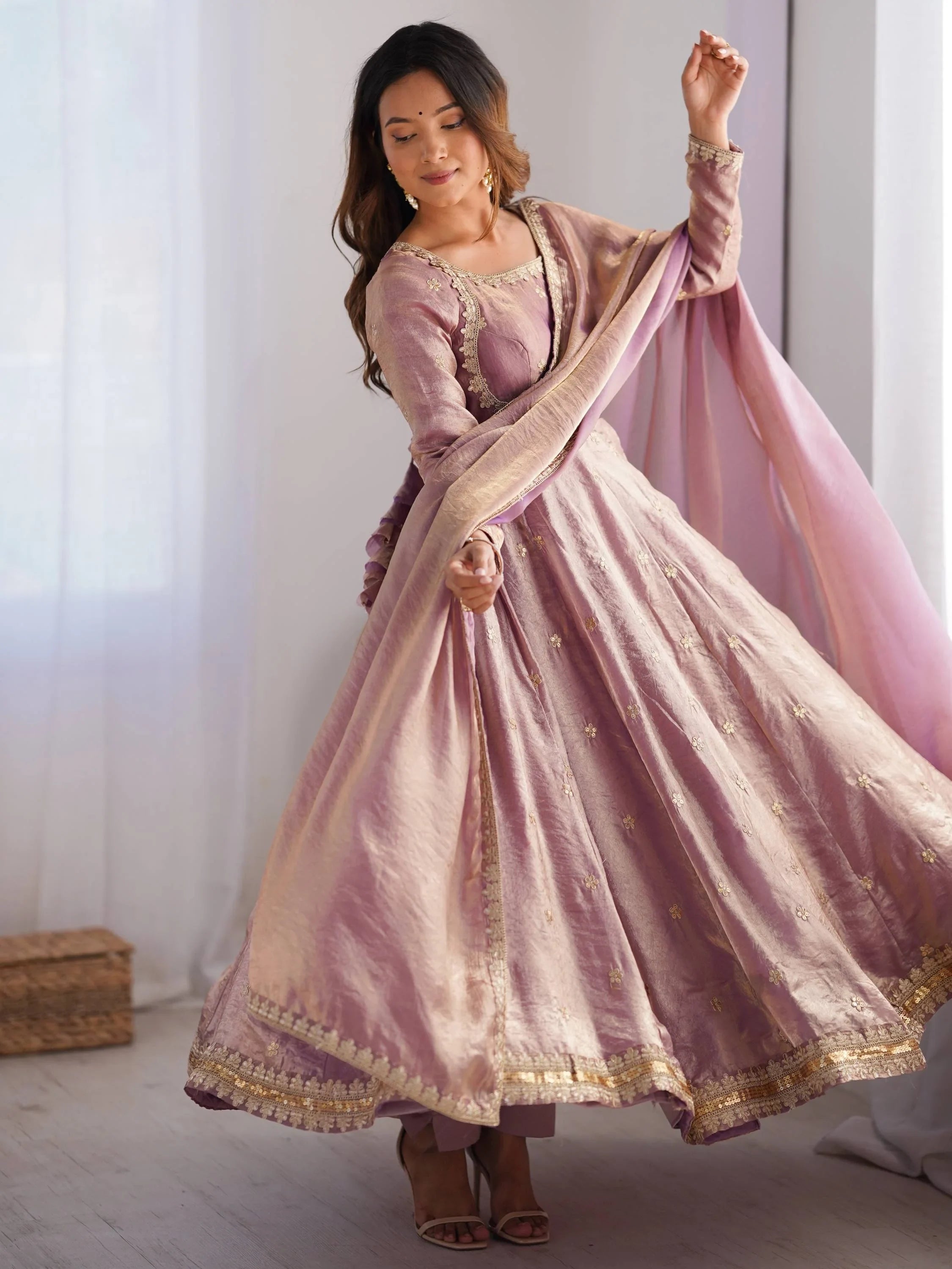 Woman in flowing pink embroidered Anarkali suit with dupatta, indoor ethnic fashion