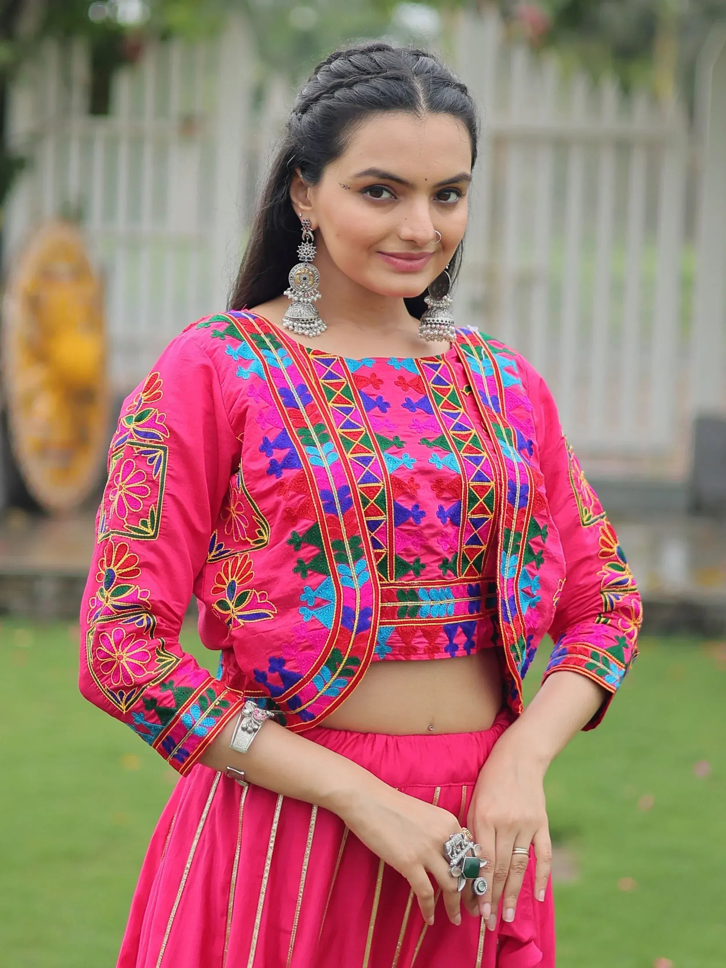 Vibrant pink embroidered lehenga choli with colorful floral patterns, perfect for festive occasions.