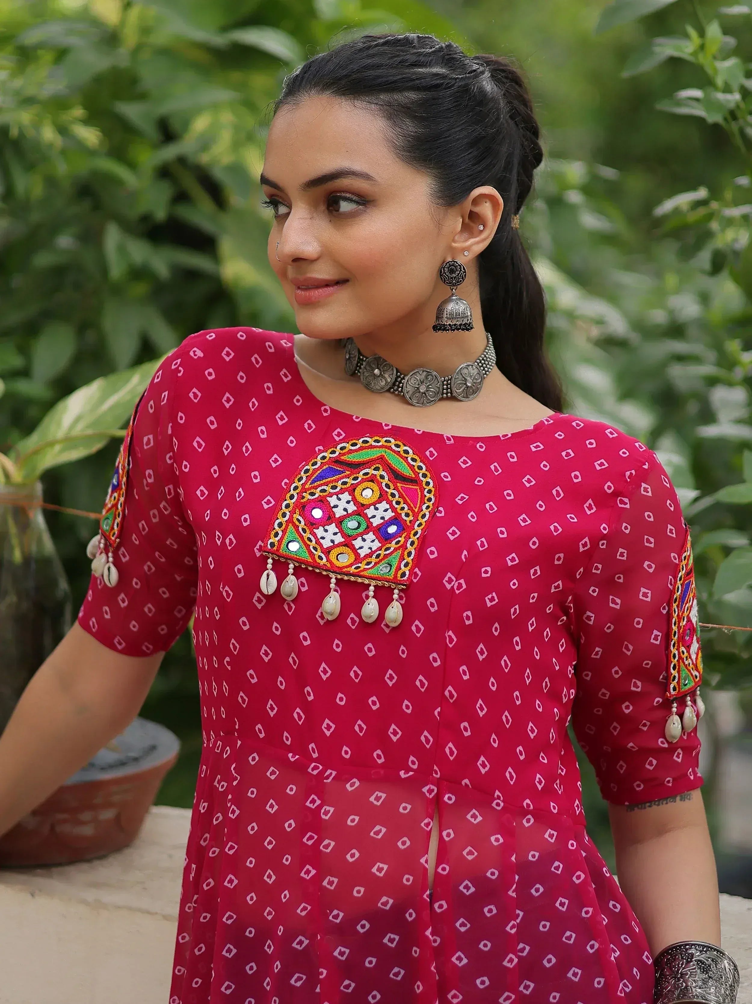 Red ethnic kurti with mirror work and cowrie shells, paired with silver jewelry for traditional Indian wear