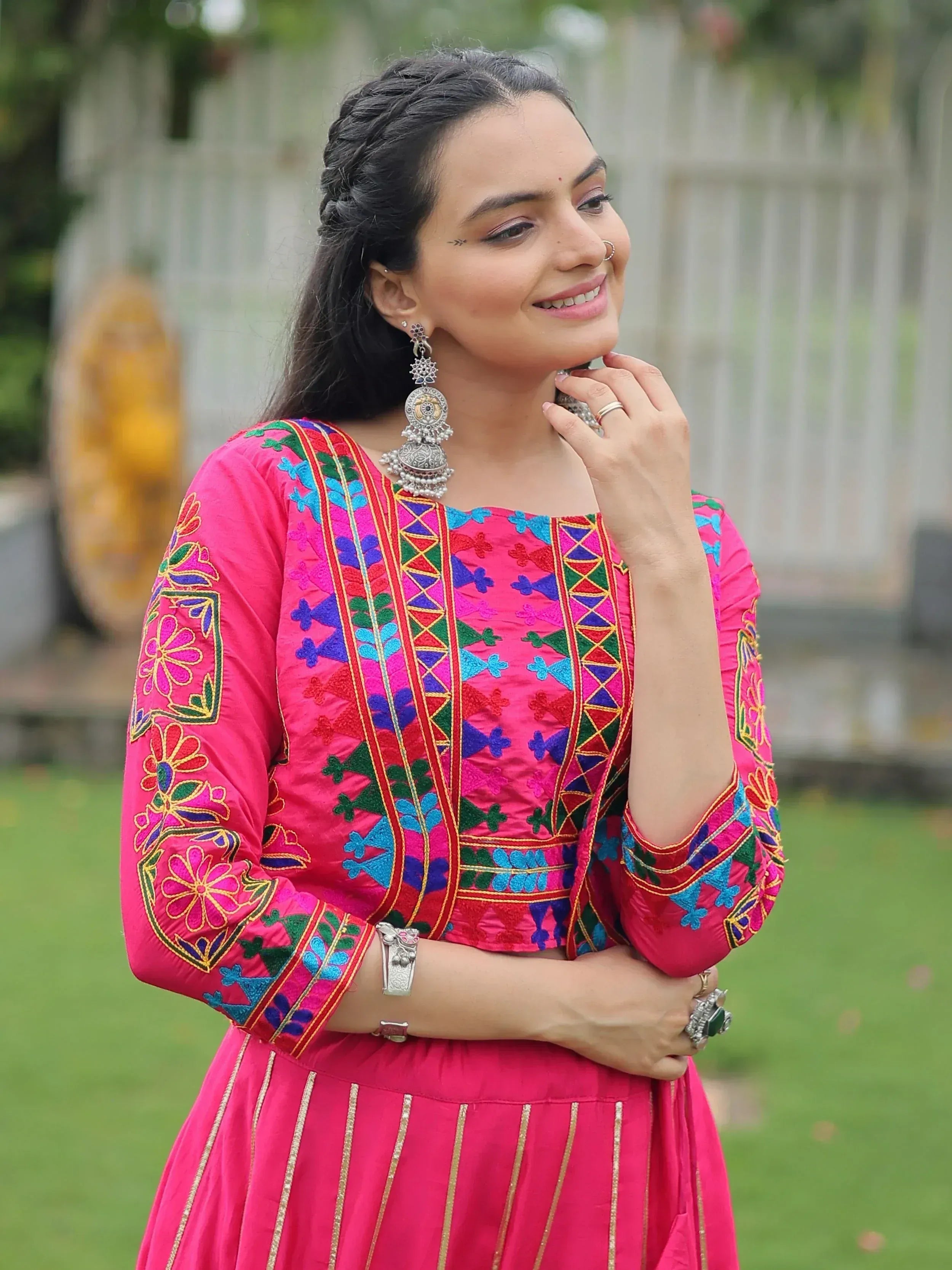Woman in vibrant pink embroidered ethnic kurta with floral patterns, silver jewelry, and traditional Indian attire