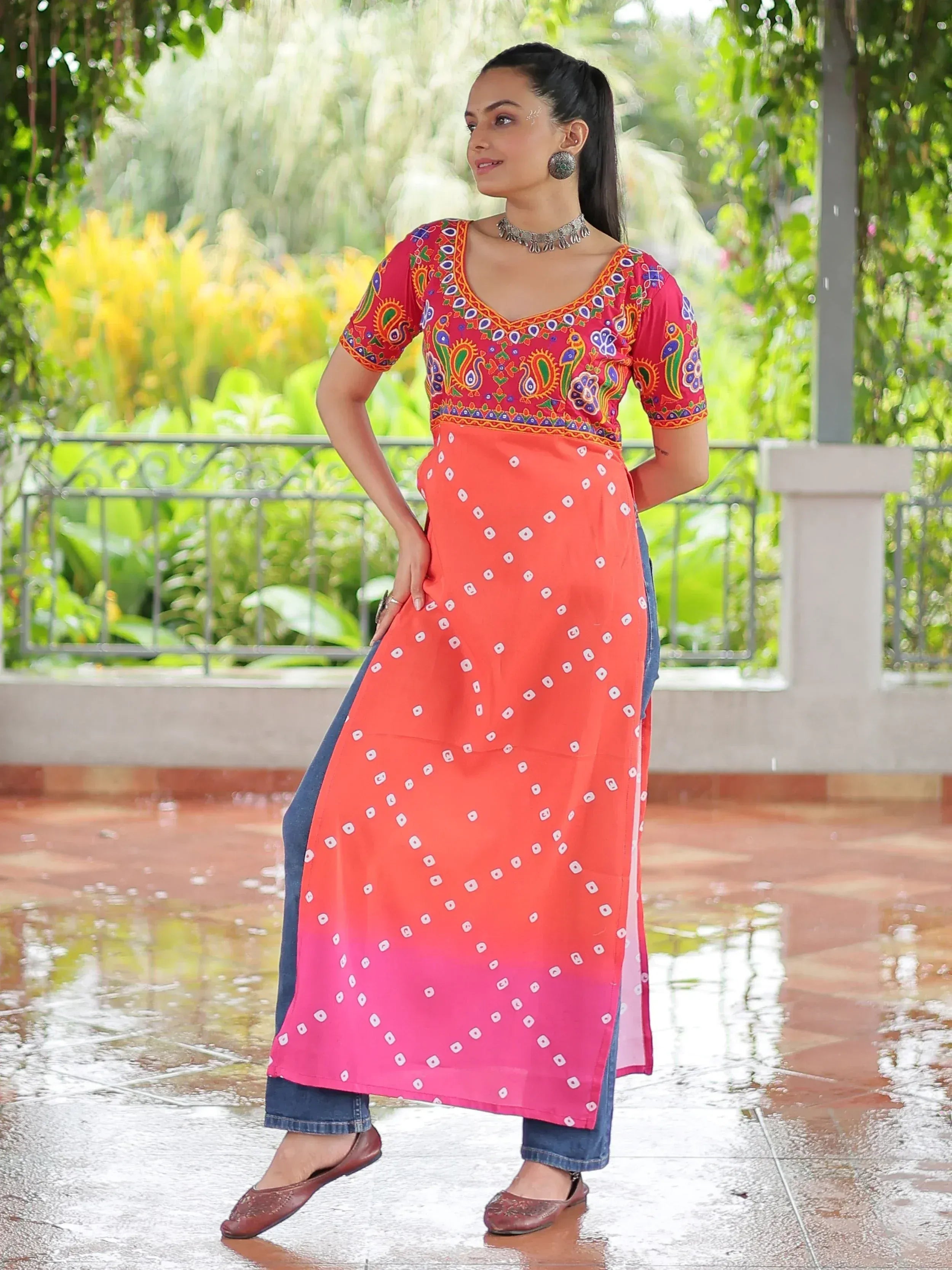 Woman in vibrant Indian ethnic kurta with paisley print, paired with denim, perfect for festive occasions