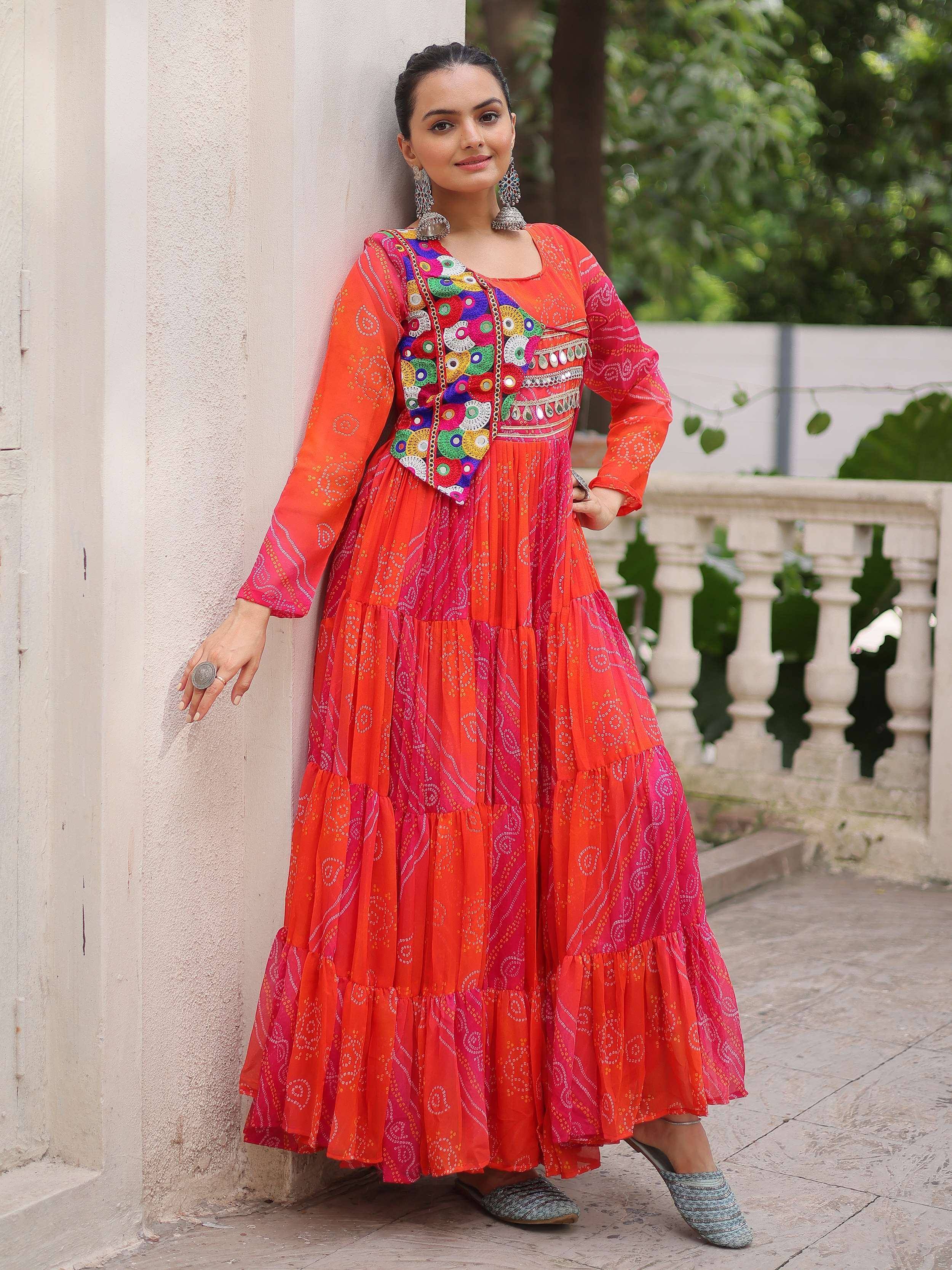 Vibrant orange and pink tiered ethnic gown with mirror work, perfect for Indian festivals and occasions.
