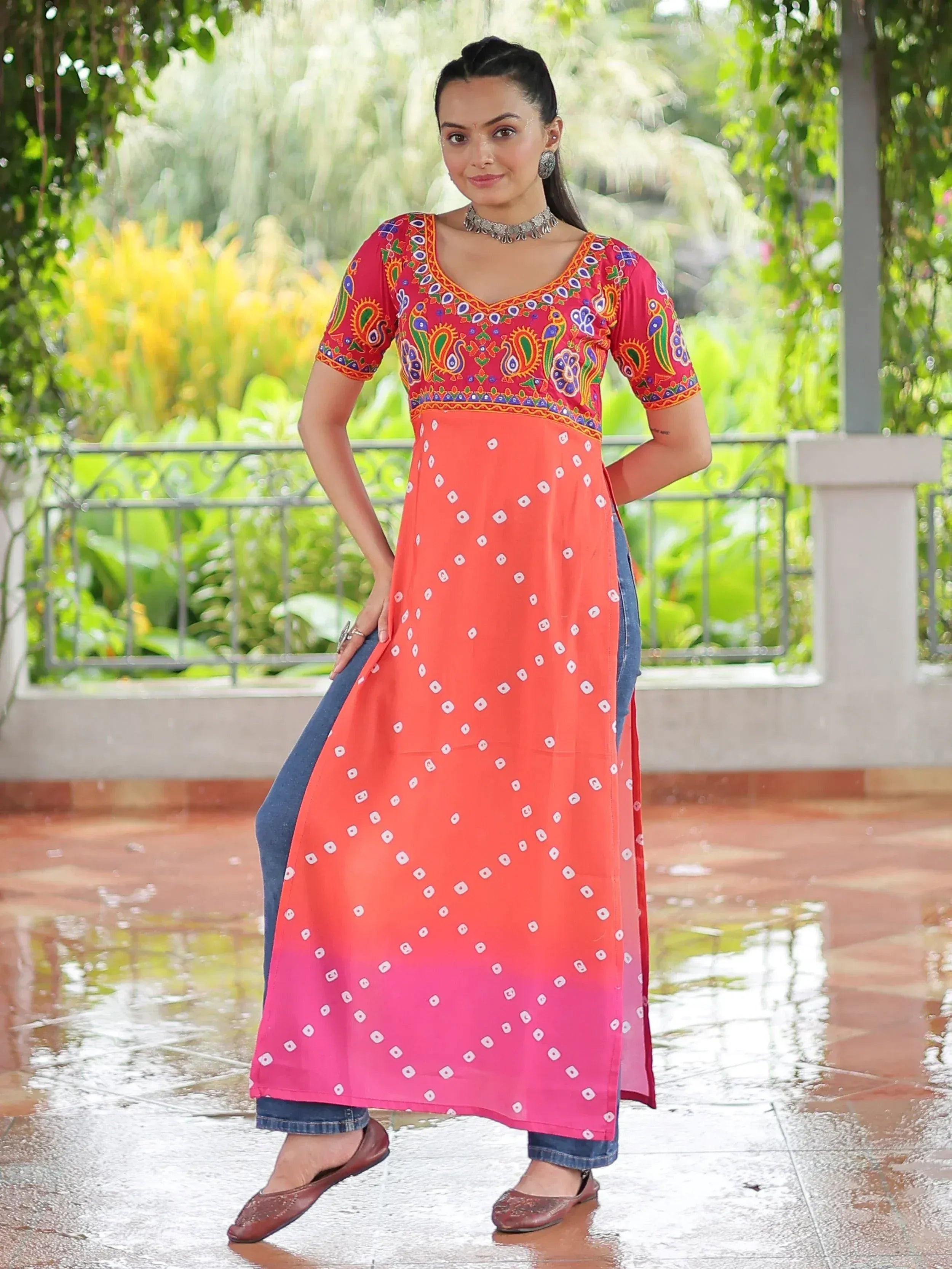 Woman in colorful printed ethnic kurti with bandhani pattern, paired with jeans, standing outdoors
