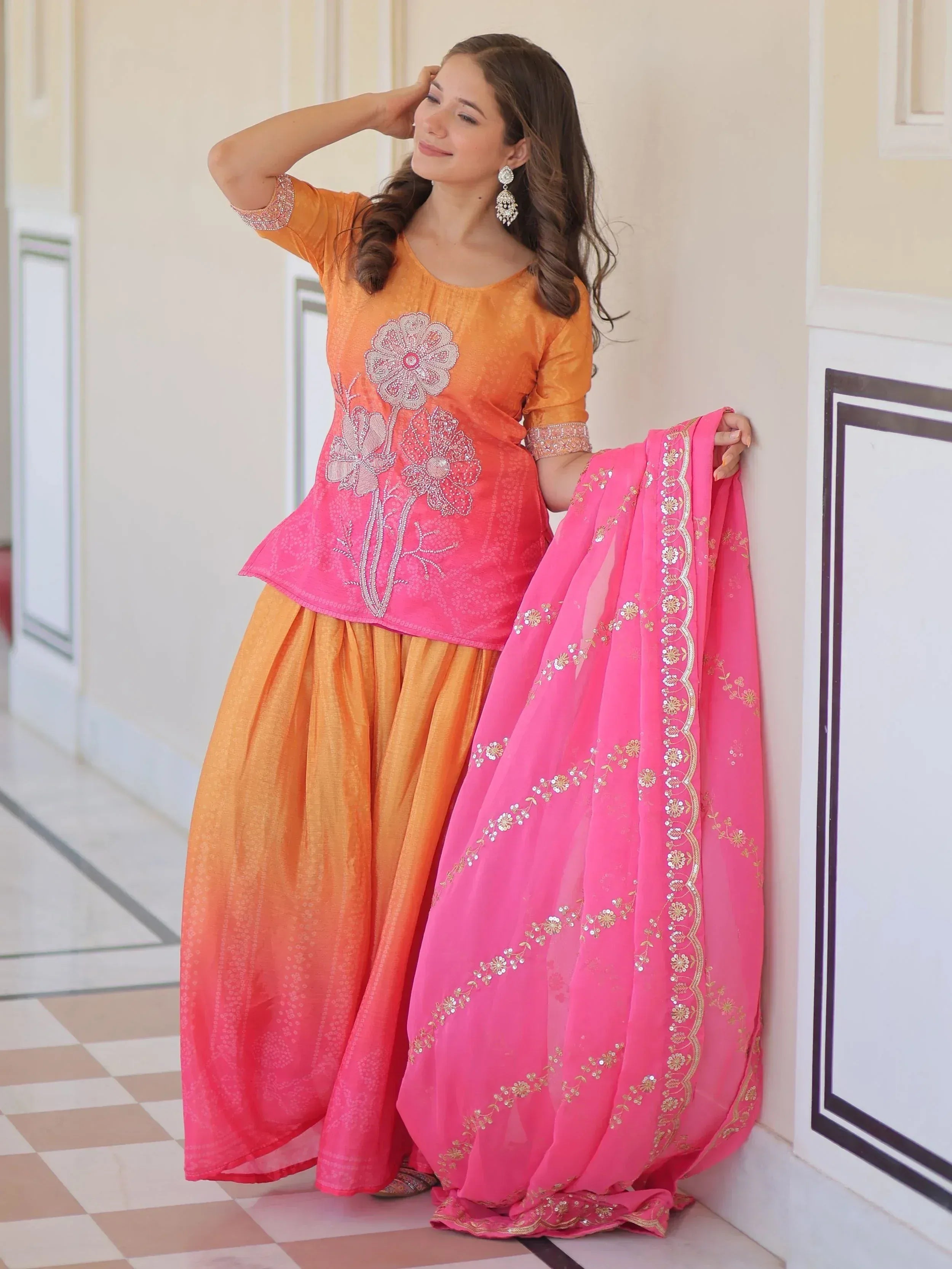 Orange and pink embroidered salwar kameez with floral motifs and matching dupatta, ideal for festive occasions.
