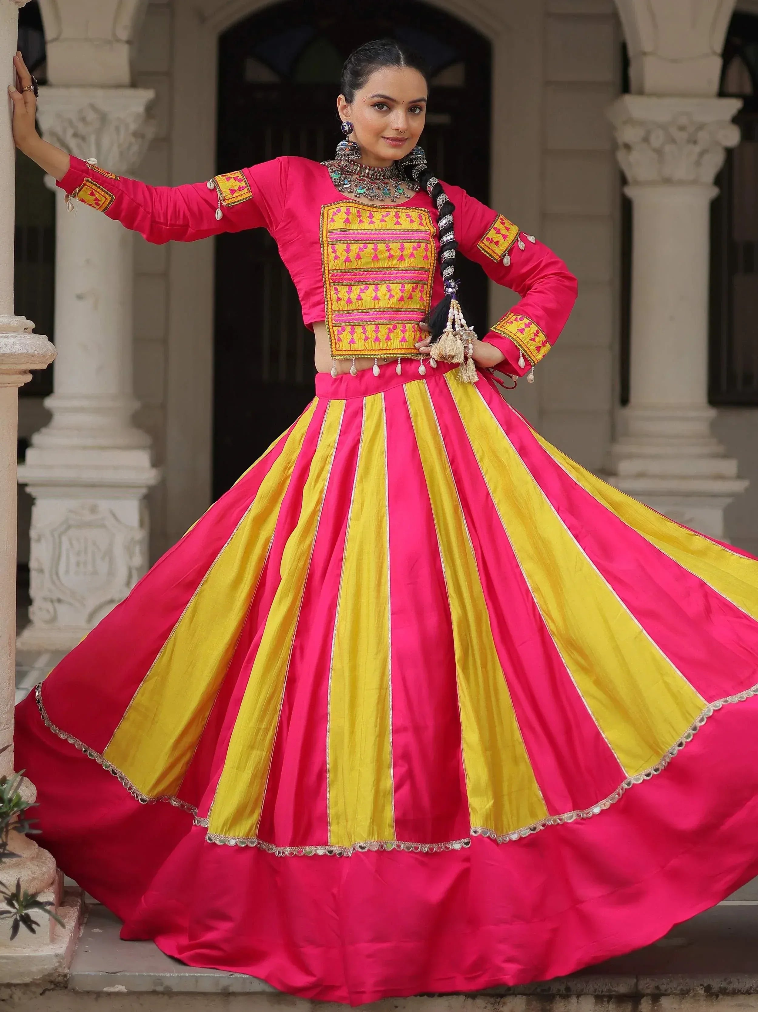 Vibrant pink and yellow striped lehenga choli with intricate embroidery and traditional jewelry