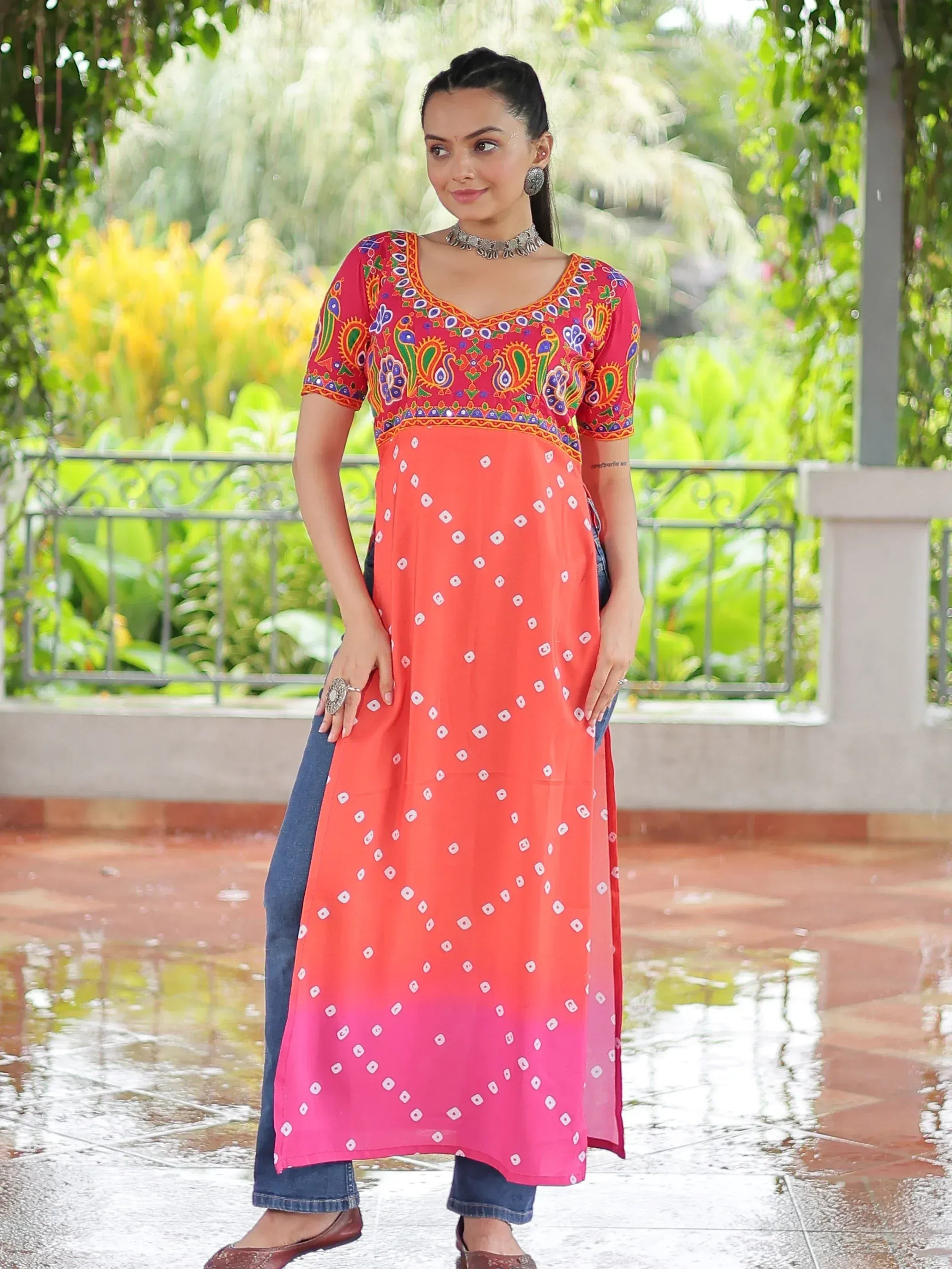 Woman in colorful embroidered ethnic kurta with bandhani print, paired with jeans, for festive Indian wear