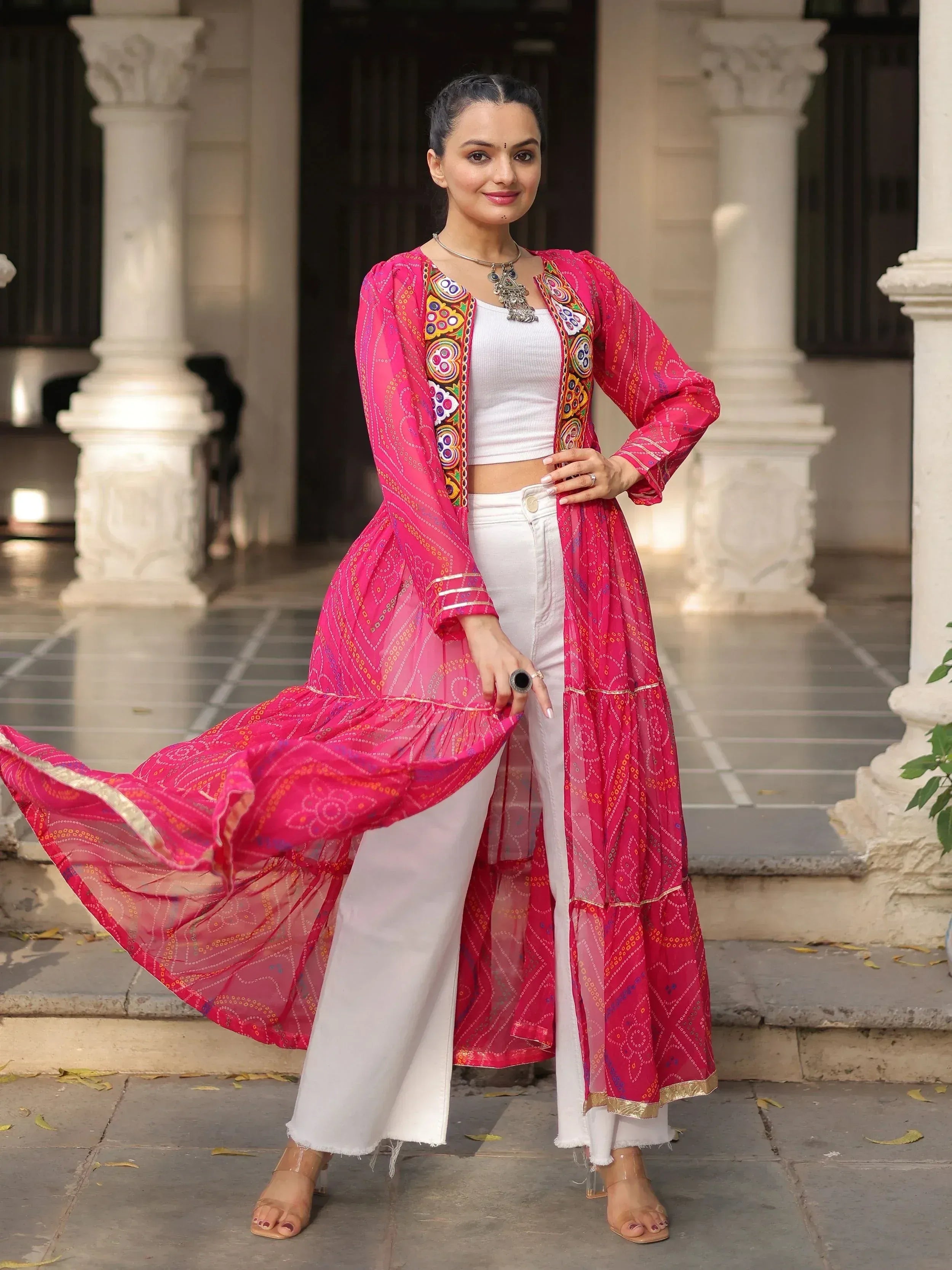 Woman in vibrant pink embroidered ethnic jacket with white pants, styled for Indian wear