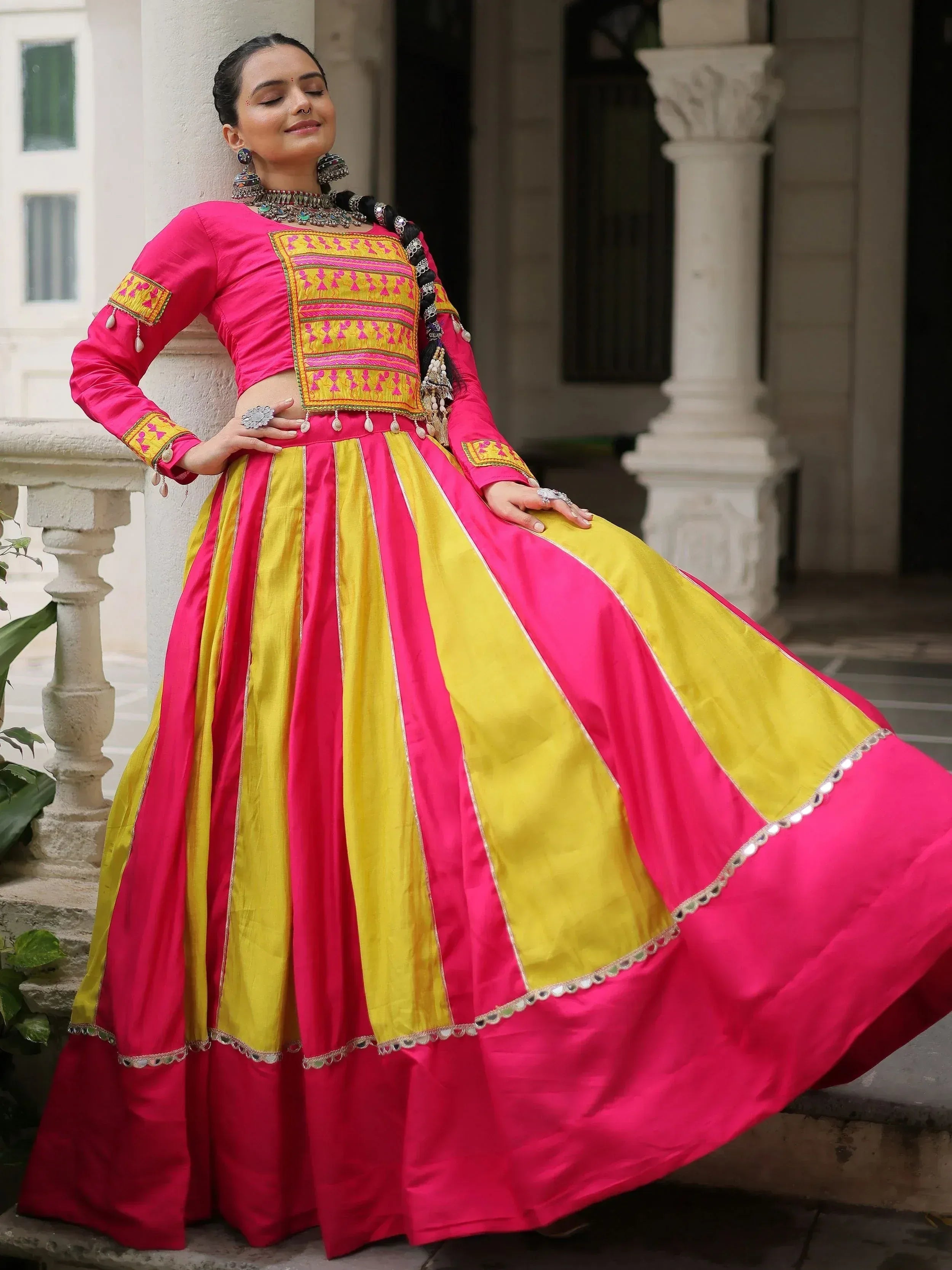 Vibrant pink and yellow embroidered lehenga choli with mirror work, perfect for Indian ethnic wear occasions.