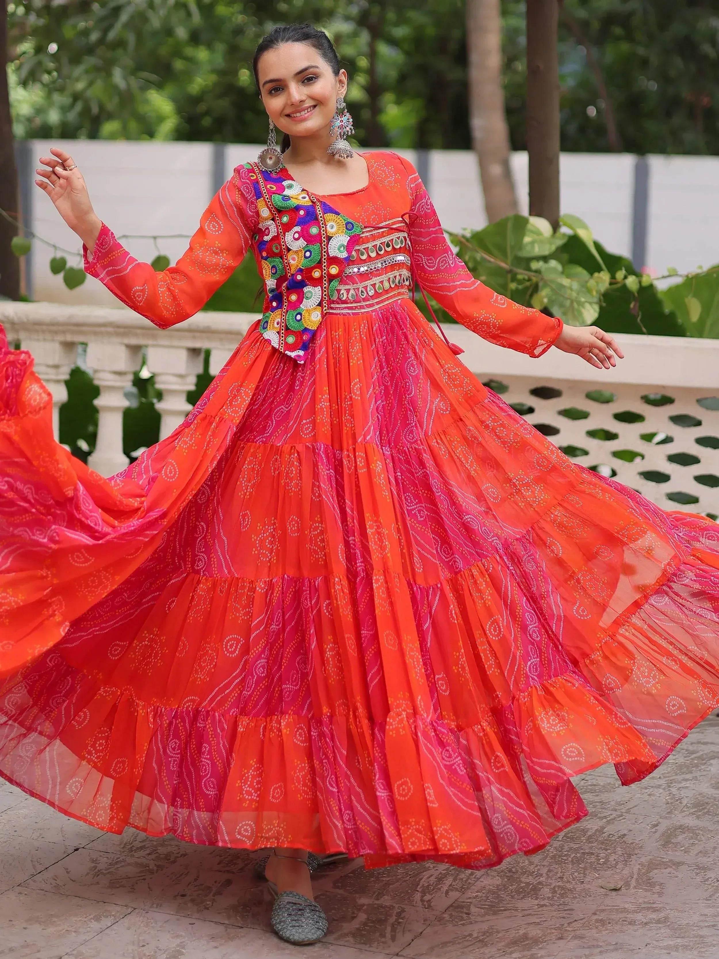 Vibrant orange and pink ethnic gown with colorful embroidery, perfect for festive occasions.