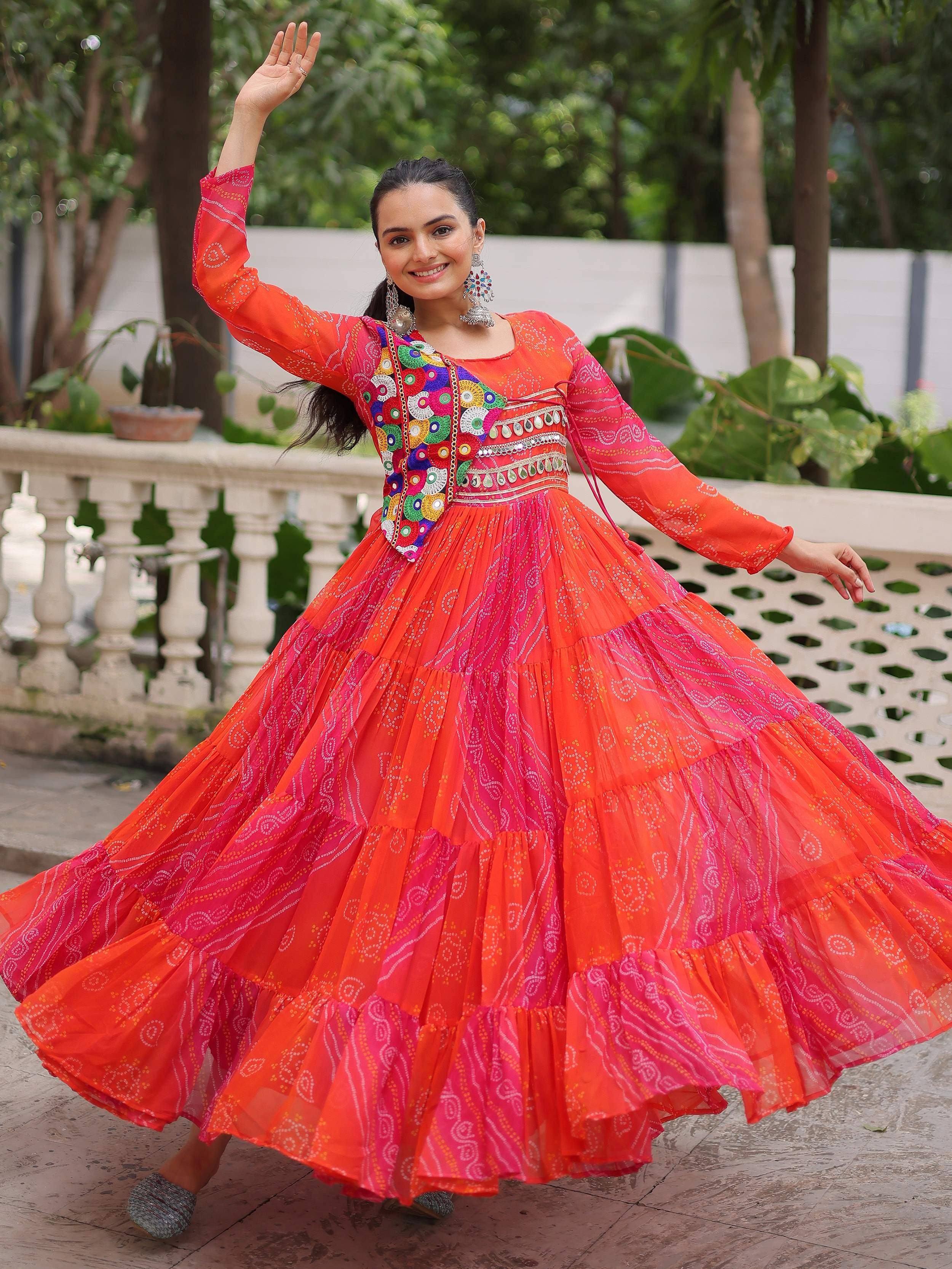 Vibrant orange and pink tiered ethnic gown with colorful embroidery, perfect for festive occasions.