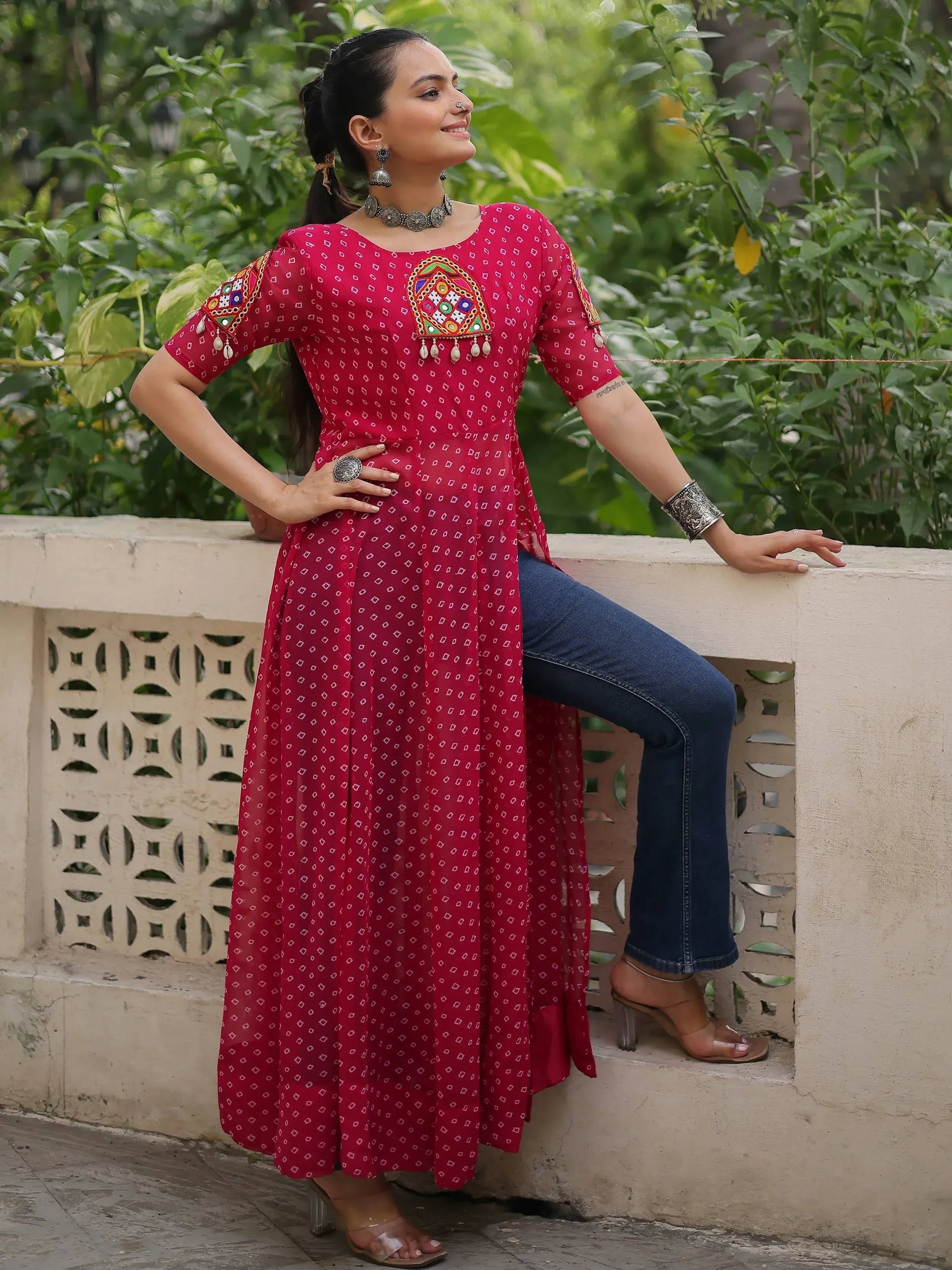 Red printed ethnic kurta with mirror work, paired with jeans and silver jewelry for casual wear