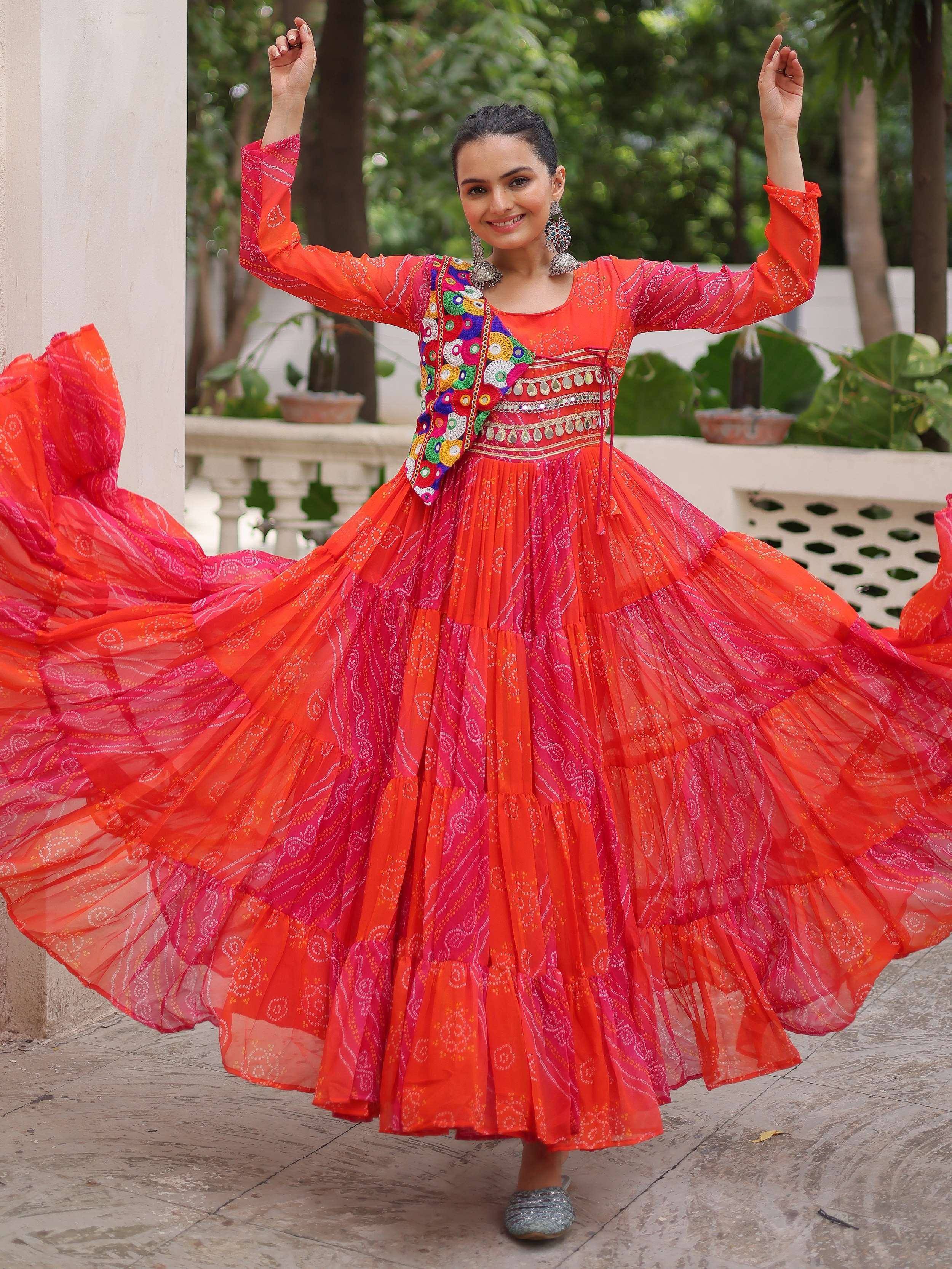 Vibrant orange and pink ethnic gown with mirror work, perfect for festive occasions and celebrations.