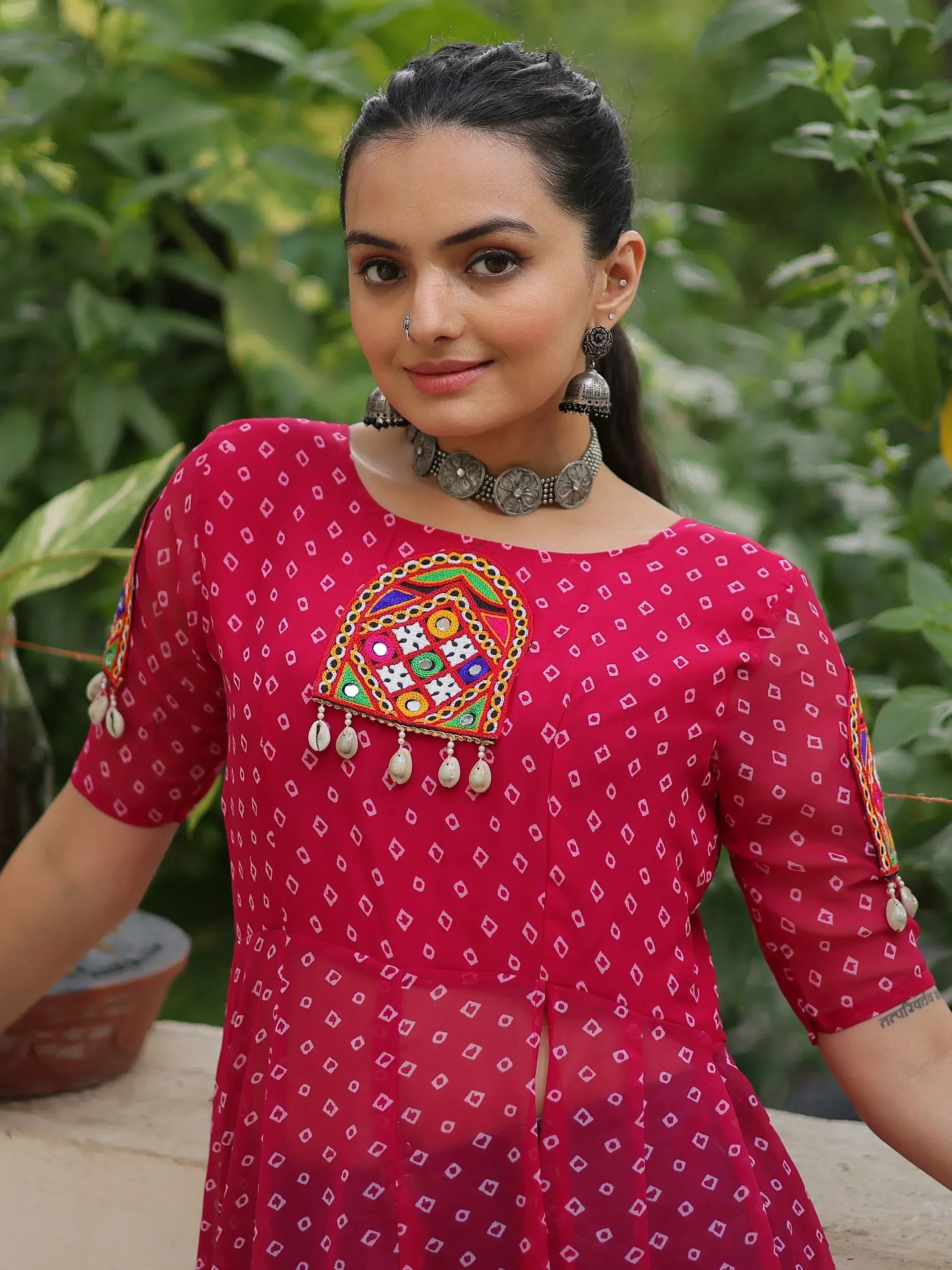 Woman in red ethnic kurta with mirror work and shell tassels, paired with silver jewelry