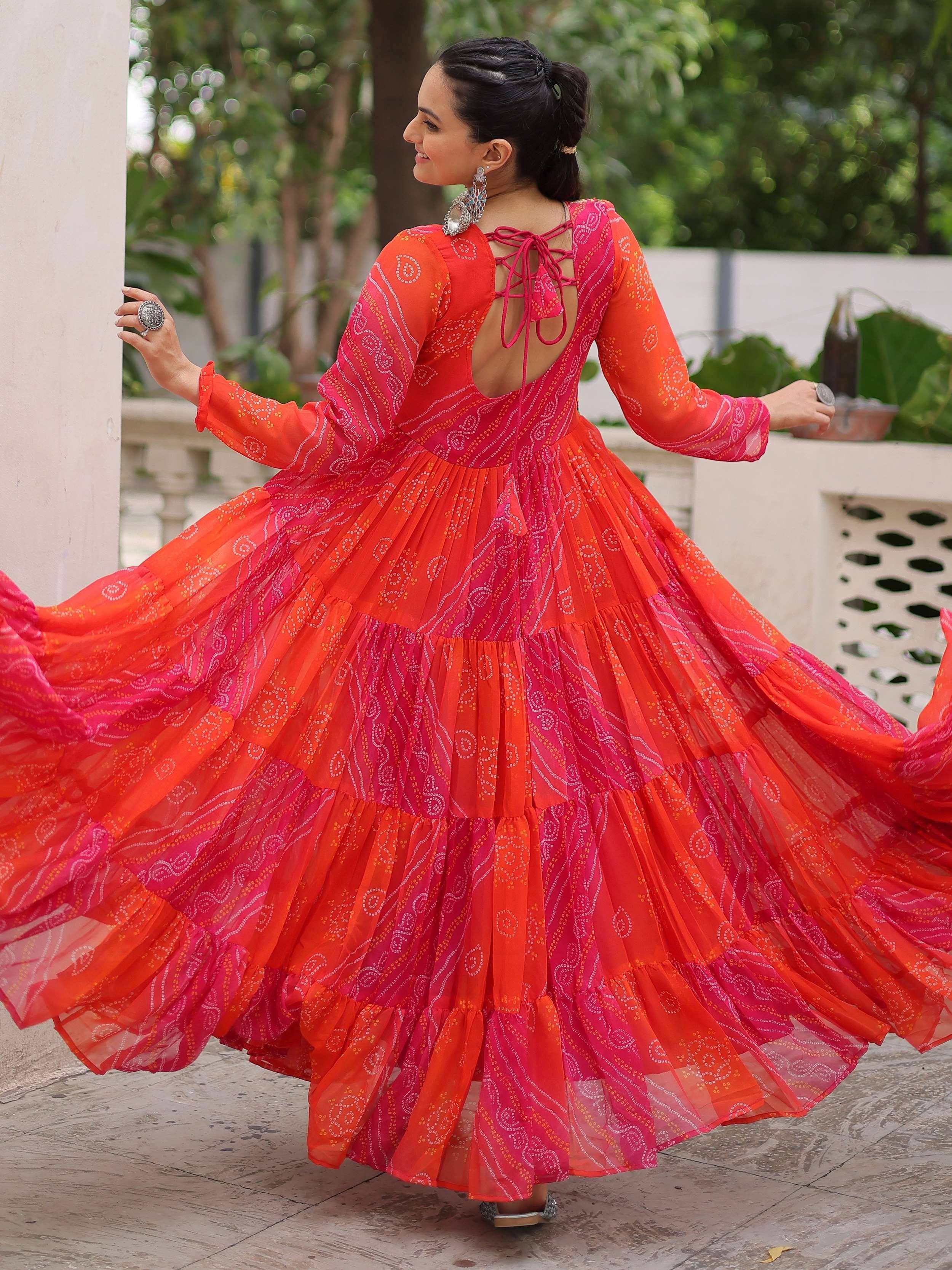 Vibrant orange and pink ethnic gown with tiered skirt, back tie detail, and bandhani print for festive occasions