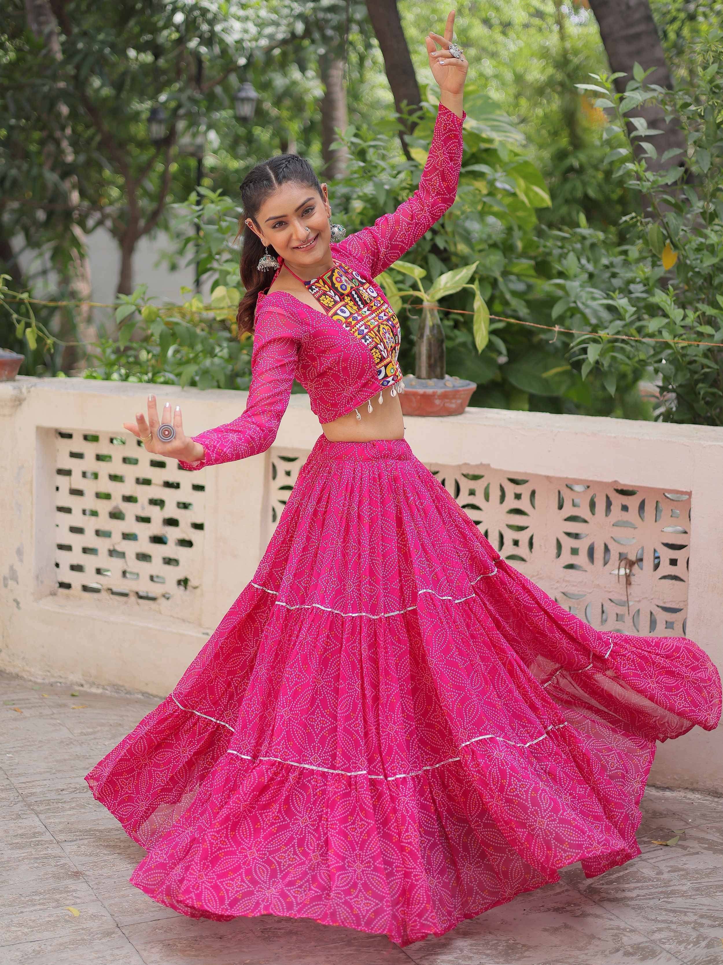 Woman in vibrant pink ethnic lehenga choli with mirror work, twirling outdoors